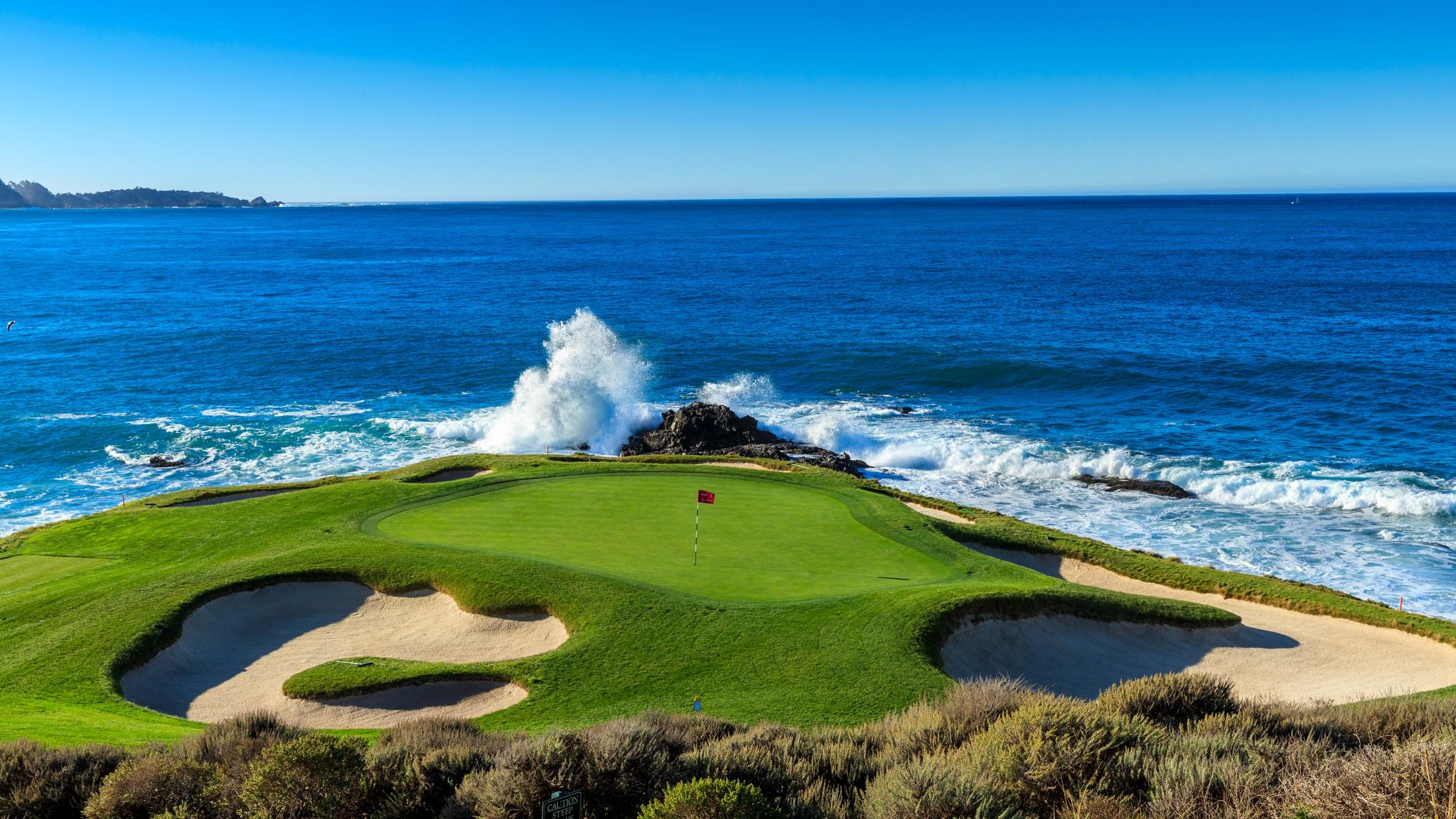 A wave crashing in towards a coastal green at The Inn at Spanish Bay & Pebble Beach