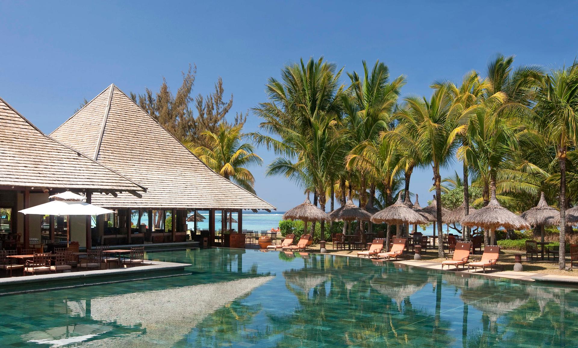 Outdoor swimming pool surrounded by palm trees at Heritage Awali