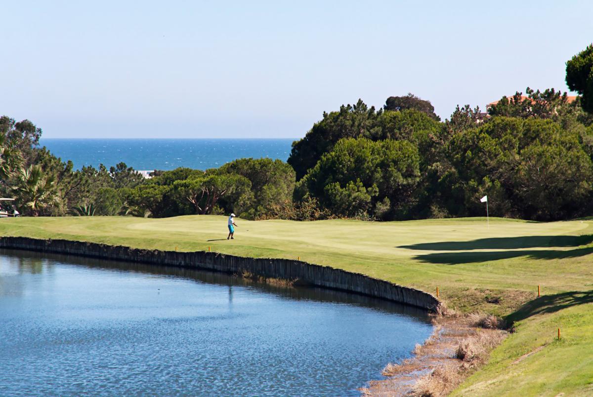 Player chipping onto the green in front of a water hazard
