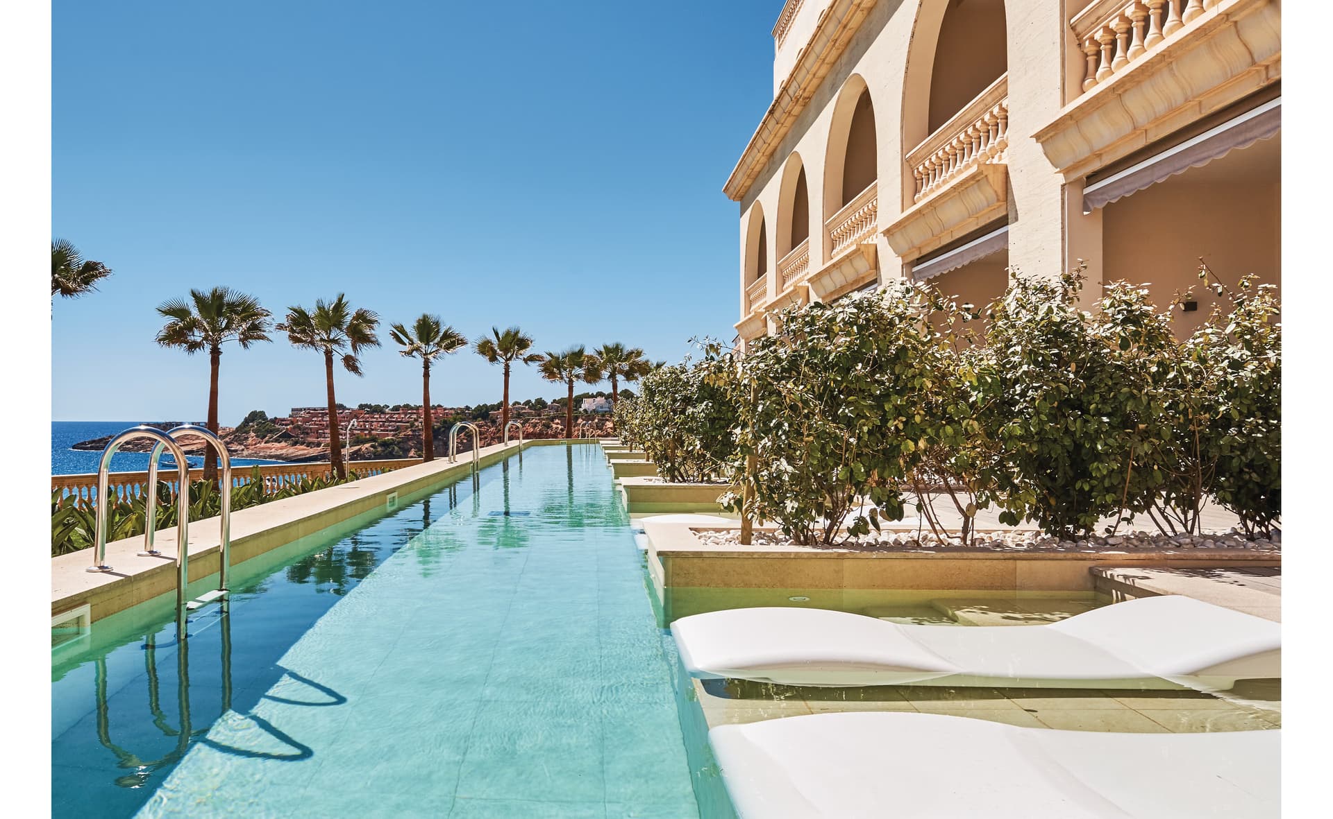 Outdoor swimming pool at Pure Salt Port Adriano lined with palm trees