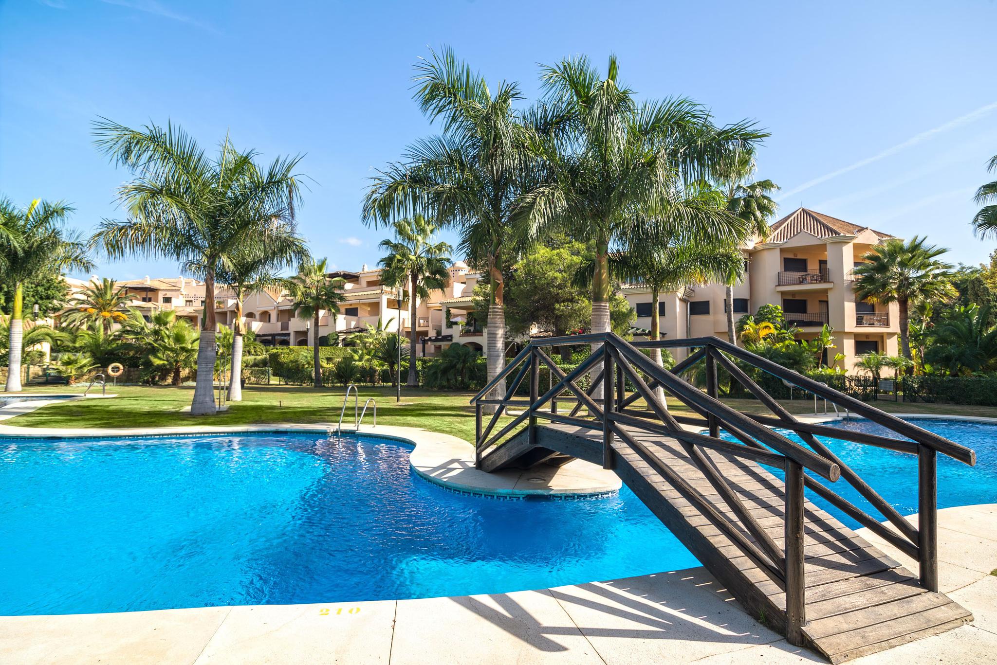 Outdoor swimming pool at Mimosas Suites Banus with a bridge to navigate it