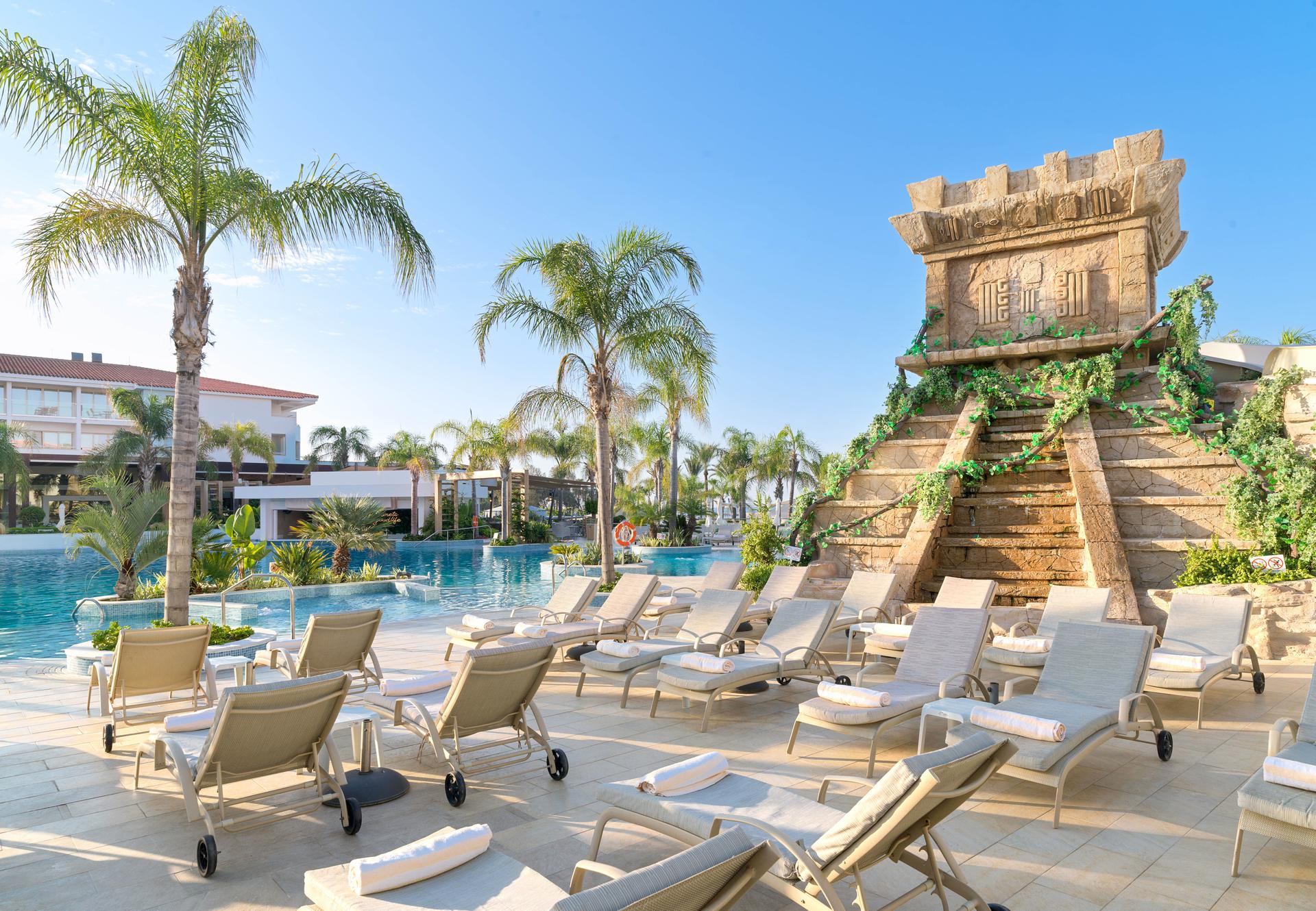 Poolside sunbeds next to a large historic structure