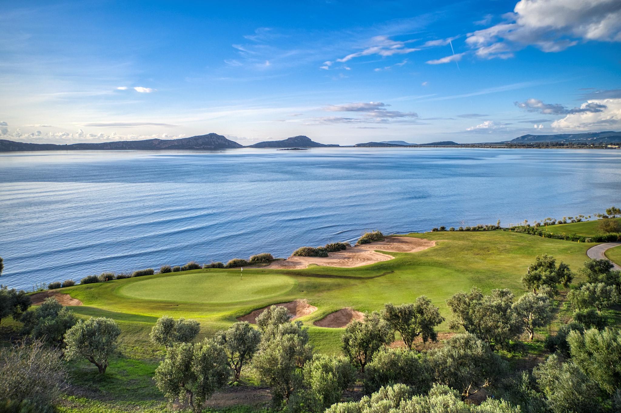 A coastal green next to sand bunkers under blue skies