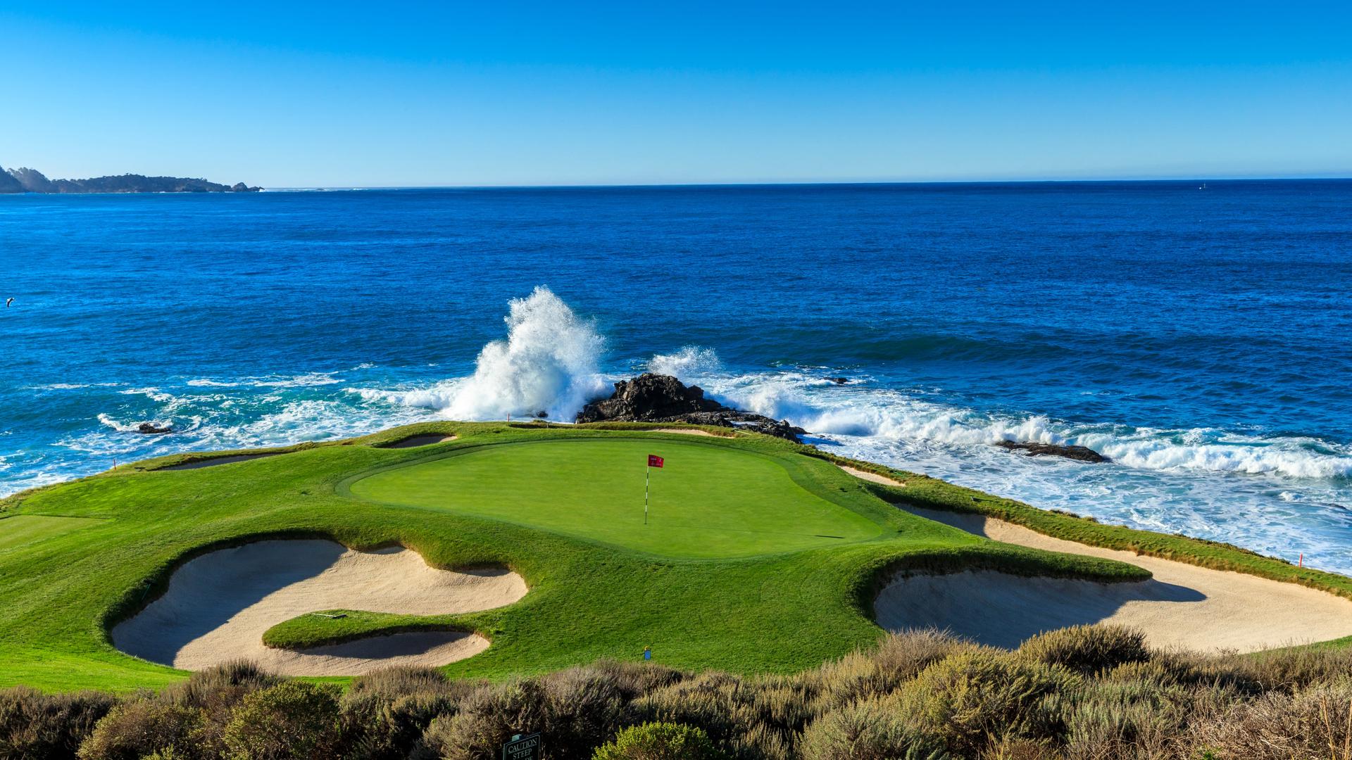 A wave crashing in towards a coastal green at The Inn at Spanish Bay & Pebble Beach