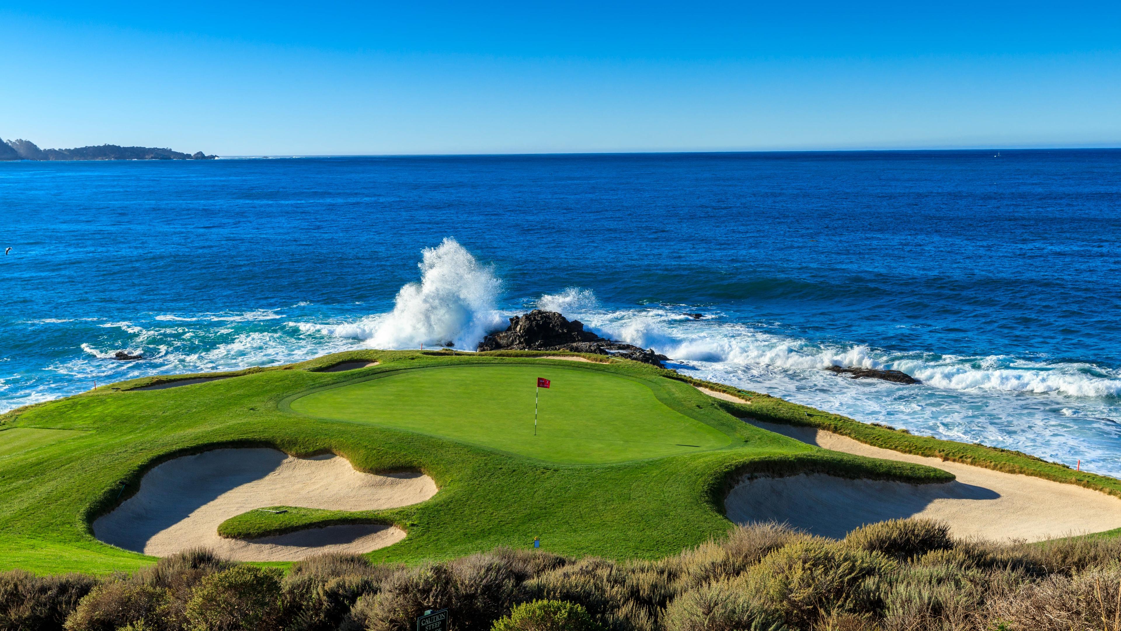 A wave crashing in towards a coastal green at The Inn at Spanish Bay & Pebble Beach