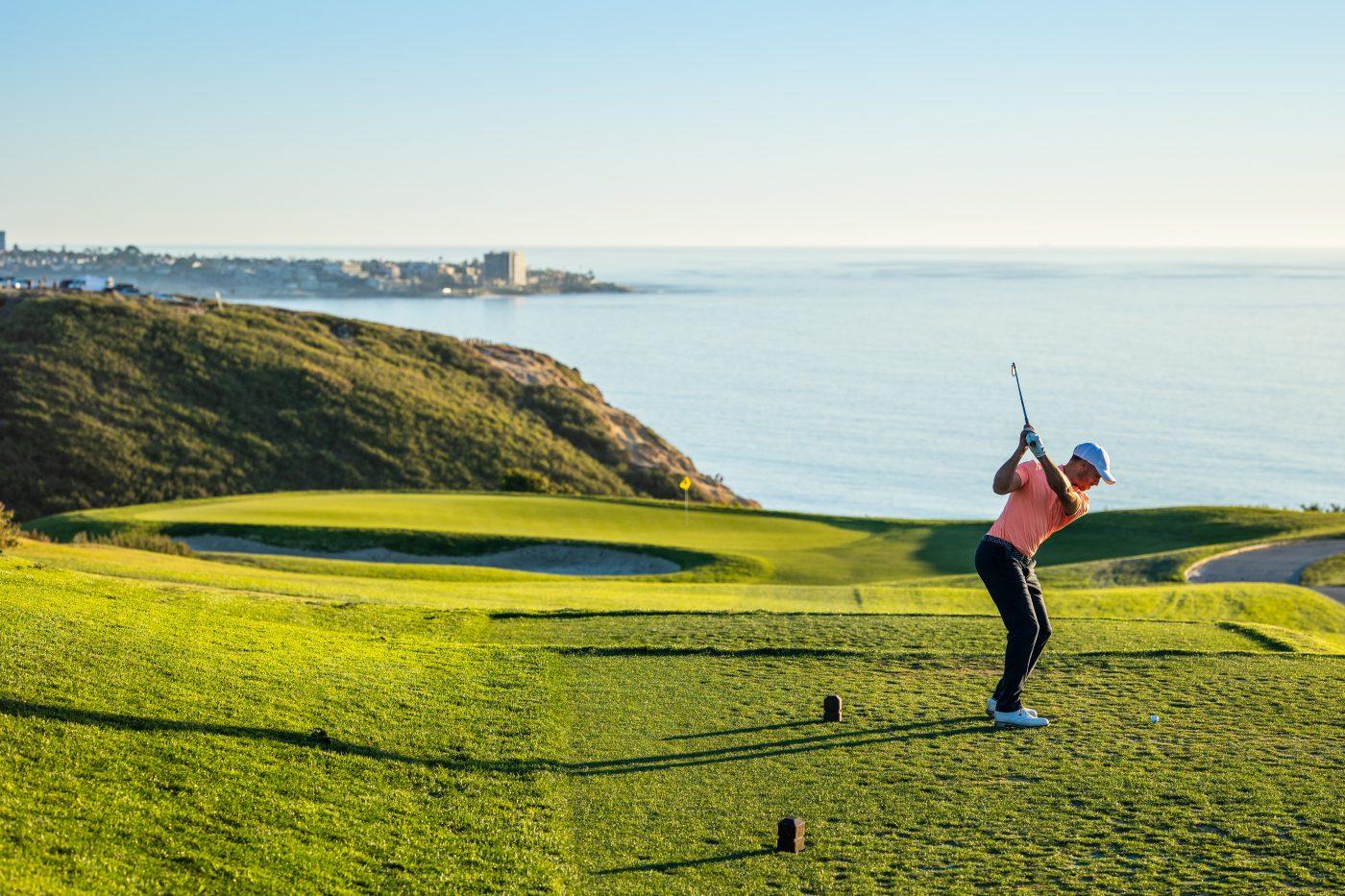 A golfer on a tee box with coastal views