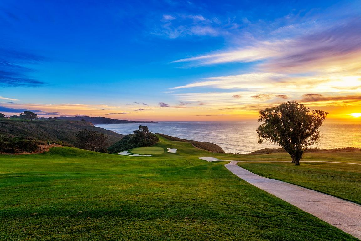 A well maintained fairway with the sun setting in the distance
