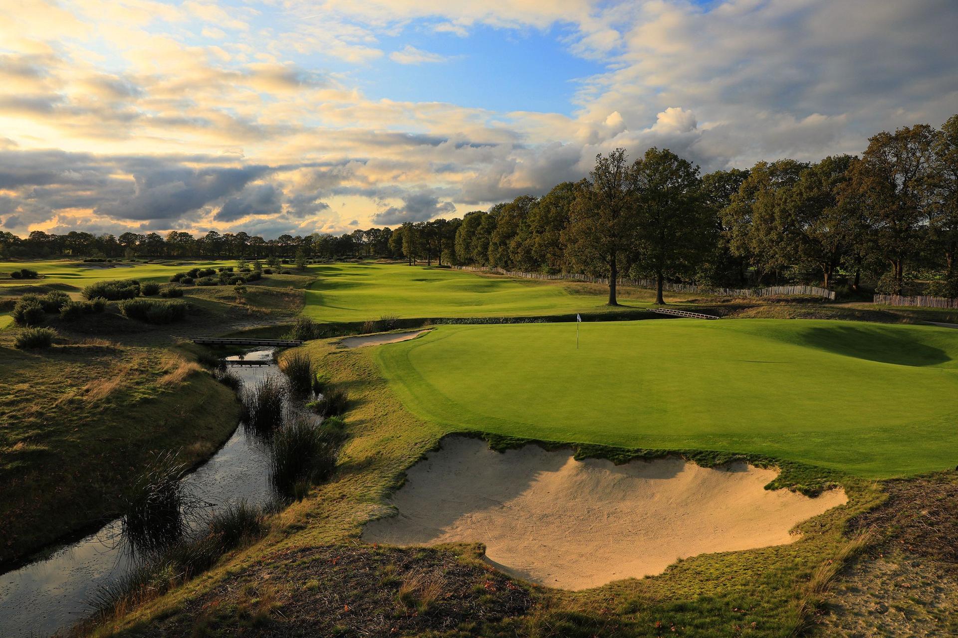 A well maintained fairway with a large sand bunker next to a water hazard