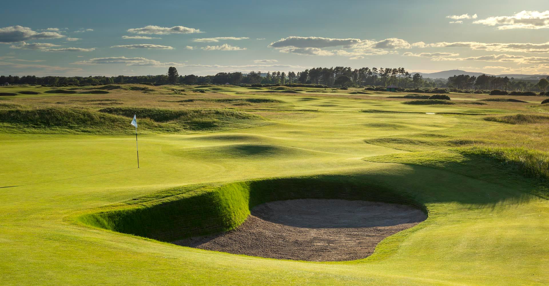 A well maintained fairway leading to a smooth green next to a sand bunker