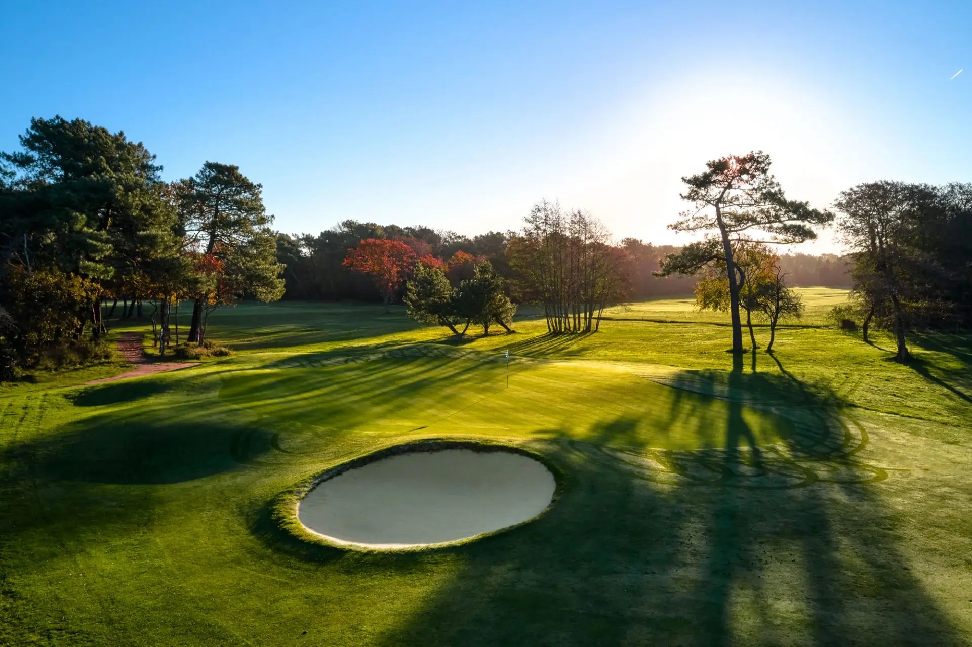 Sun shining over a well maintained fairway with a sand bunker