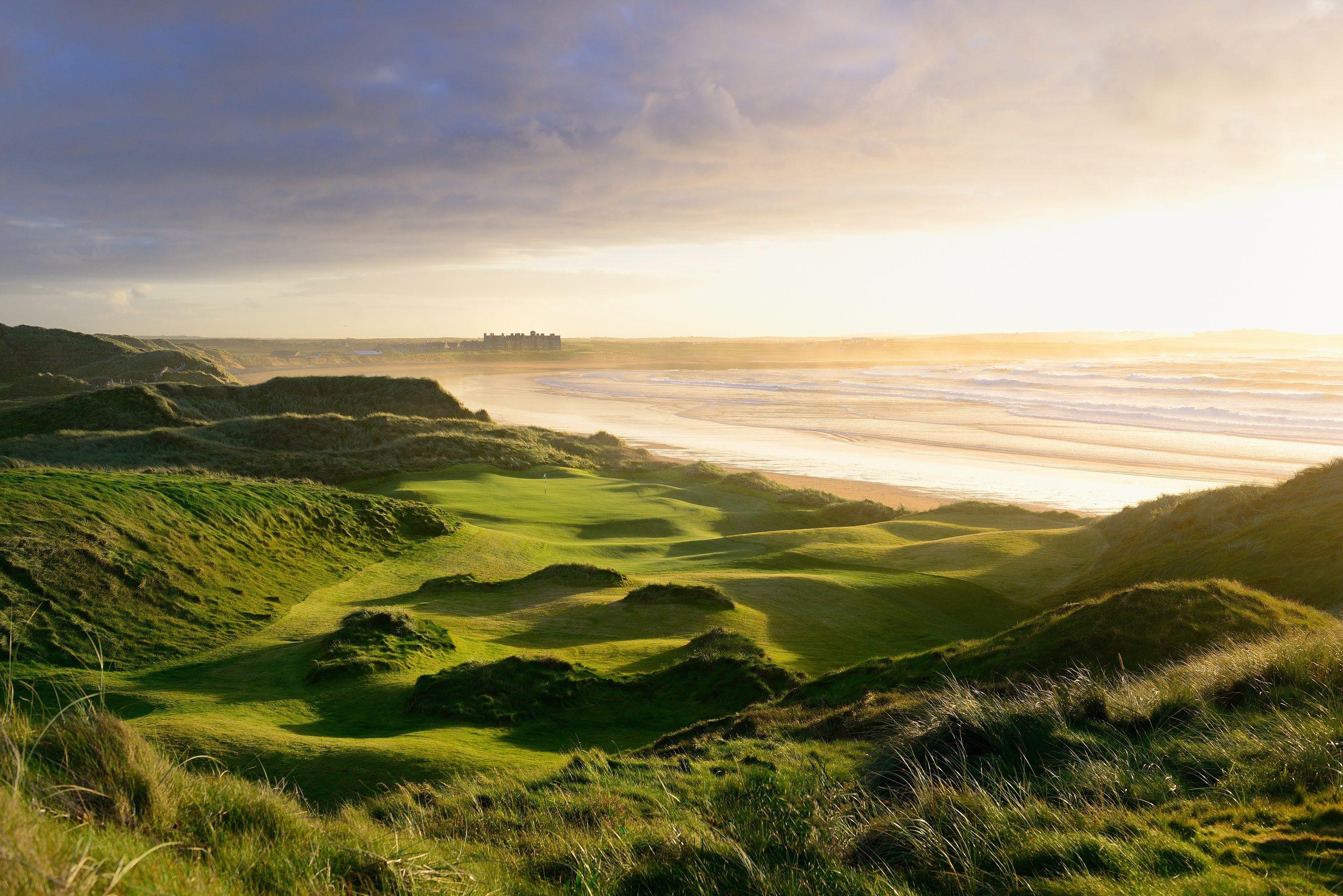 Overhead view of a coastal green with the sun setting in the distance