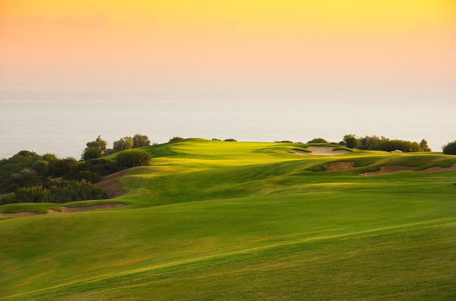 Sun setting over a coastal green at Aphrodite Hills Resort
