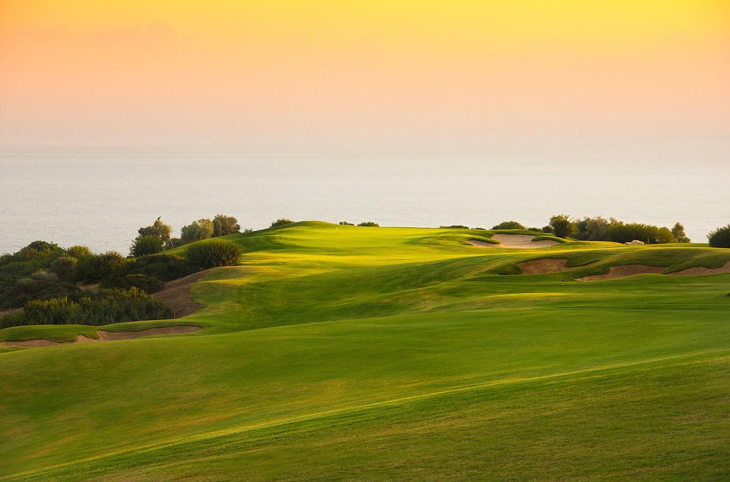 Sun setting over a coastal green at Aphrodite Hills Resort