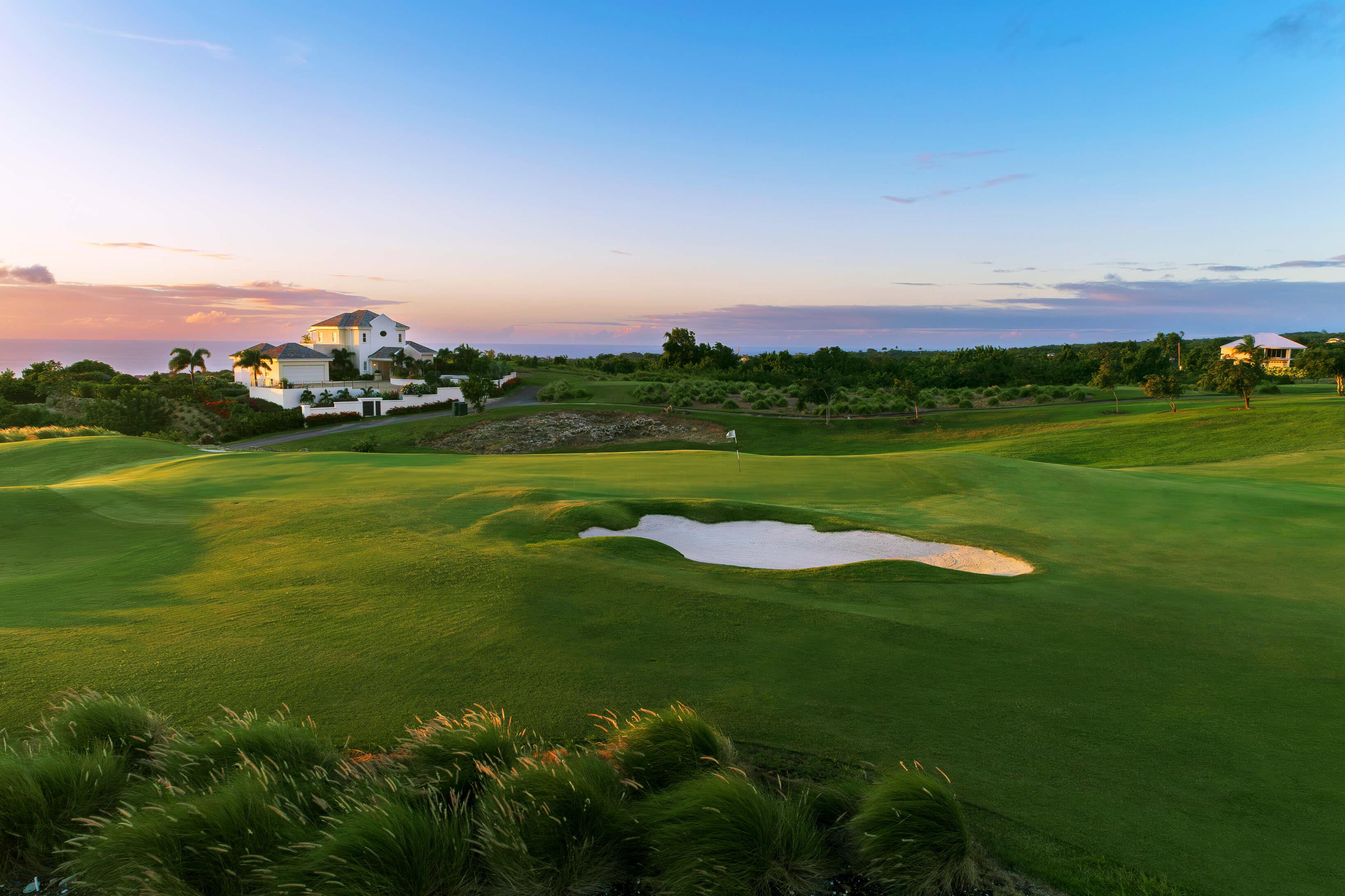 A well maintained fairway with a sand bunker with coastal views