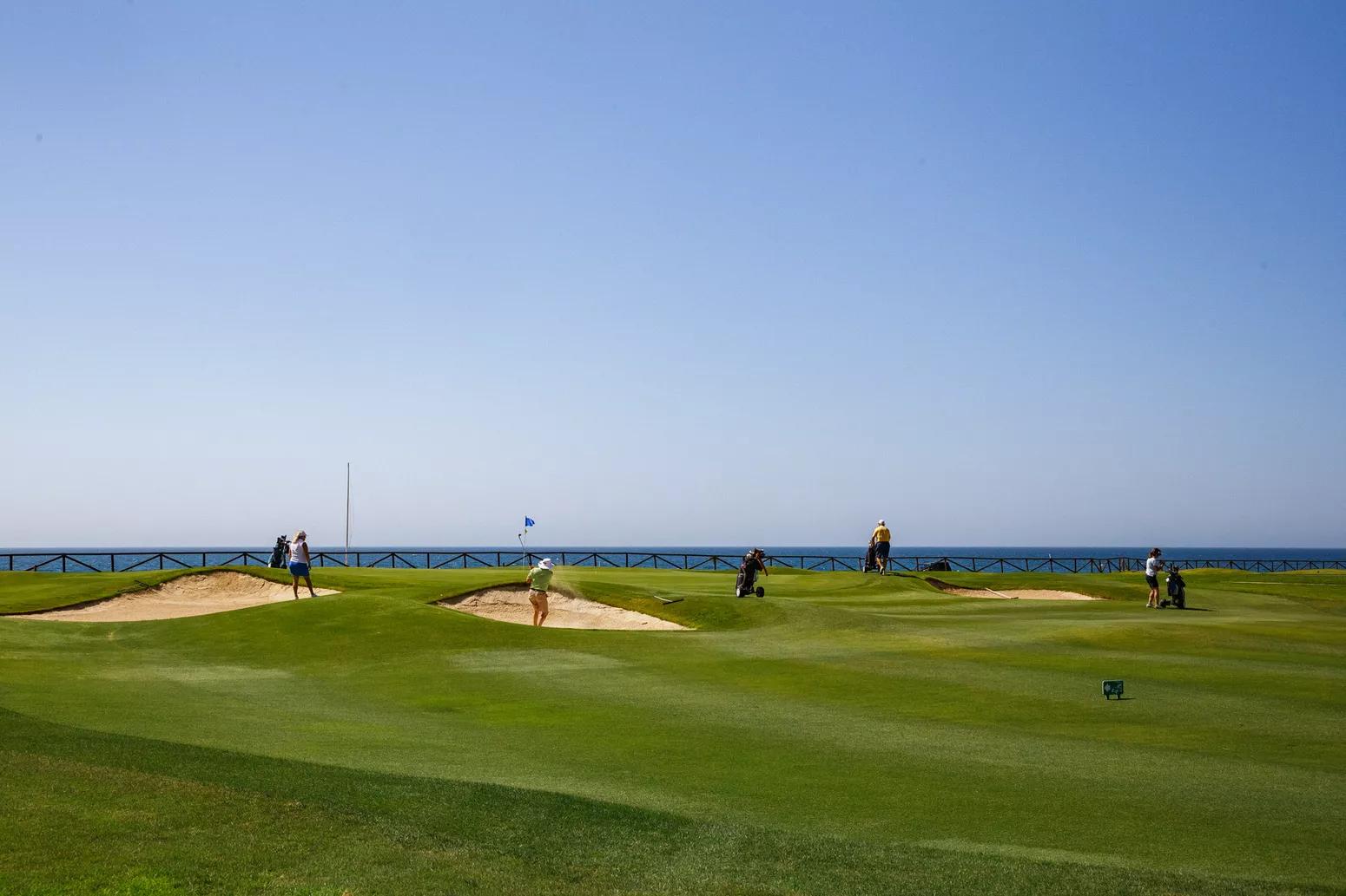a well maintained fairway with sand bunkers under clear blue skies