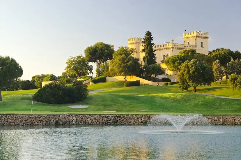 Water hazard (foreground) in front of a green with the castle-faced clubhouse in the background