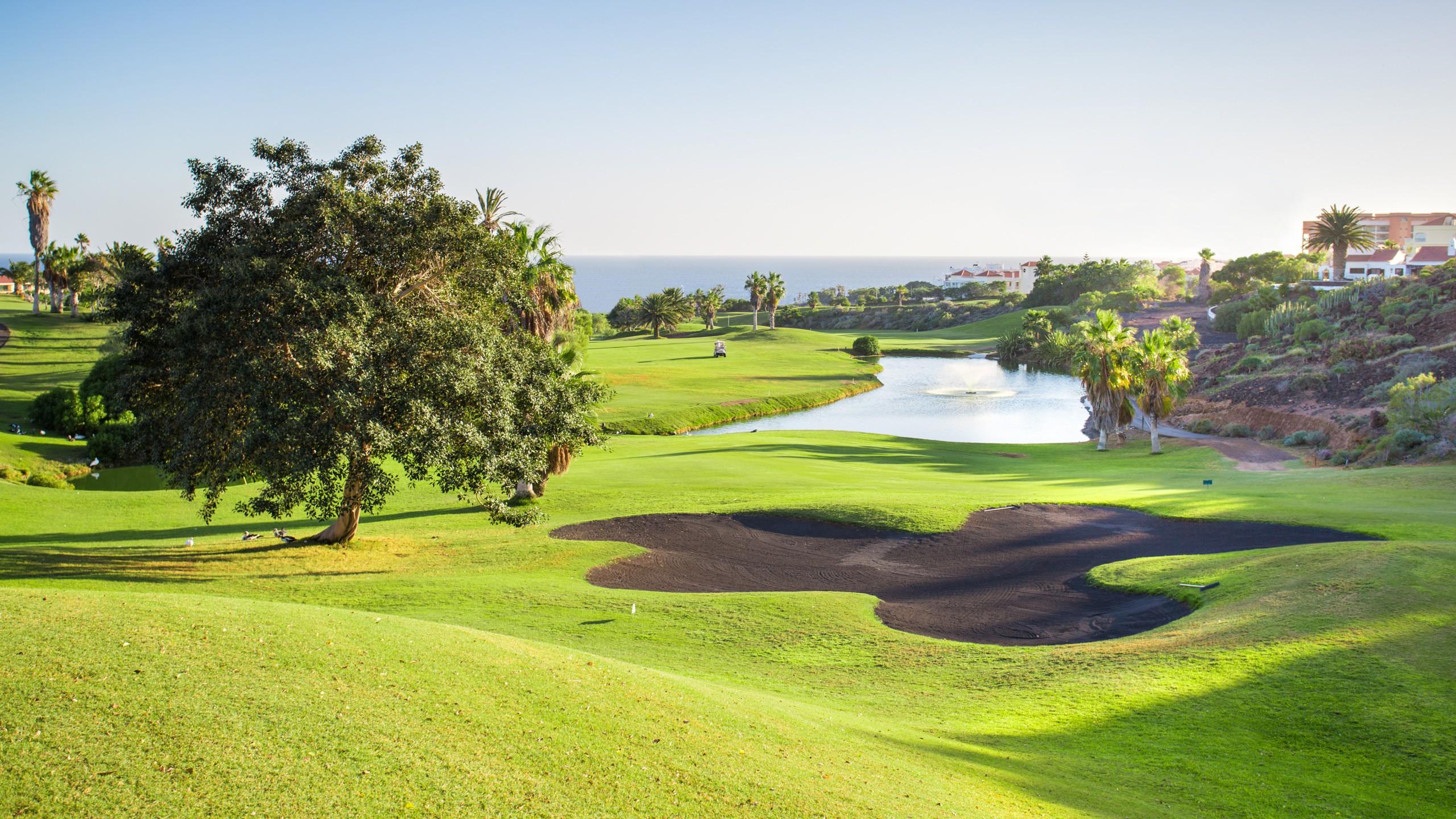 A well maintained fairway nestled with a black sand bunker