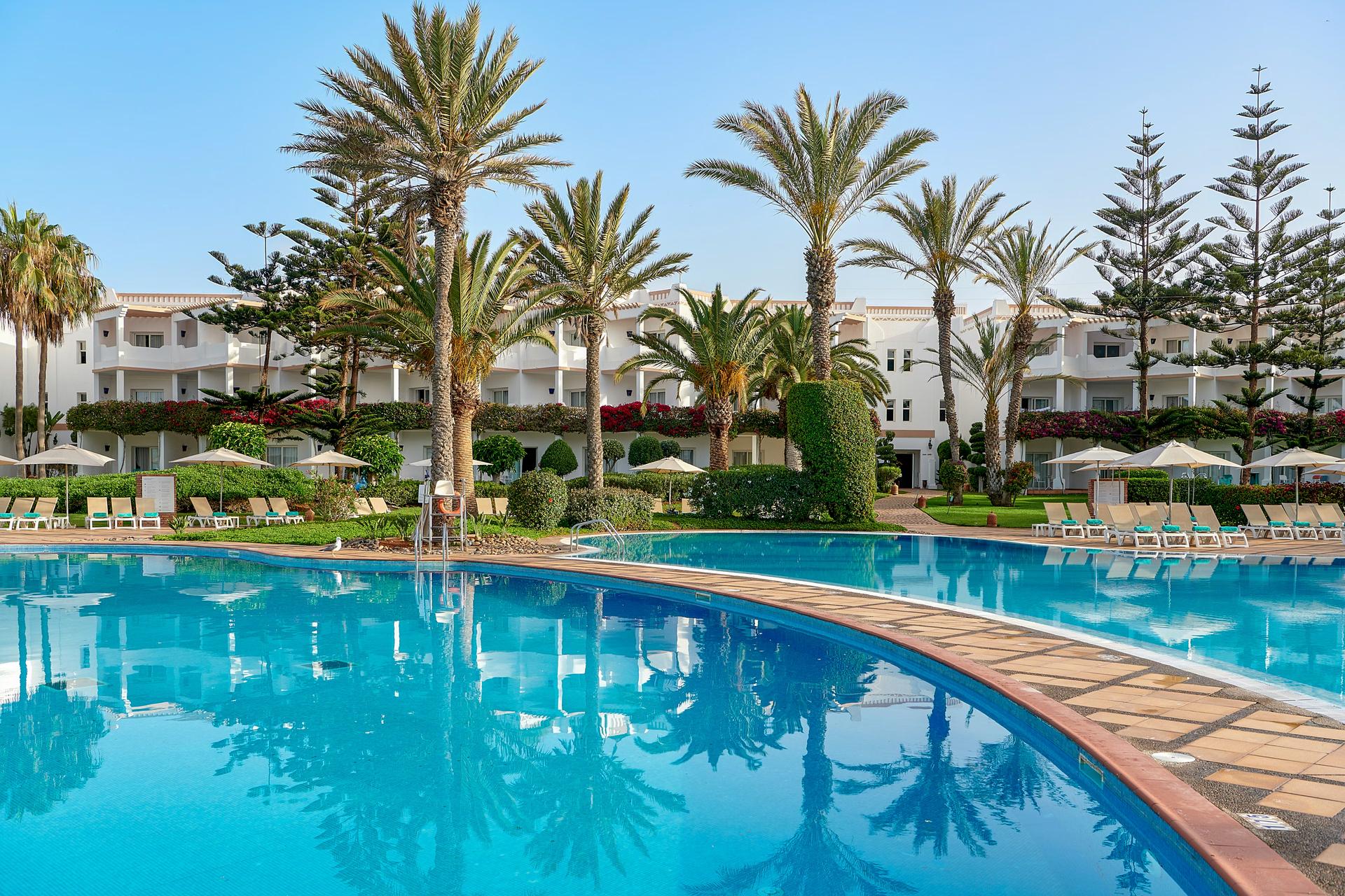 Outdoor swimming pool surrounded by palm trees
