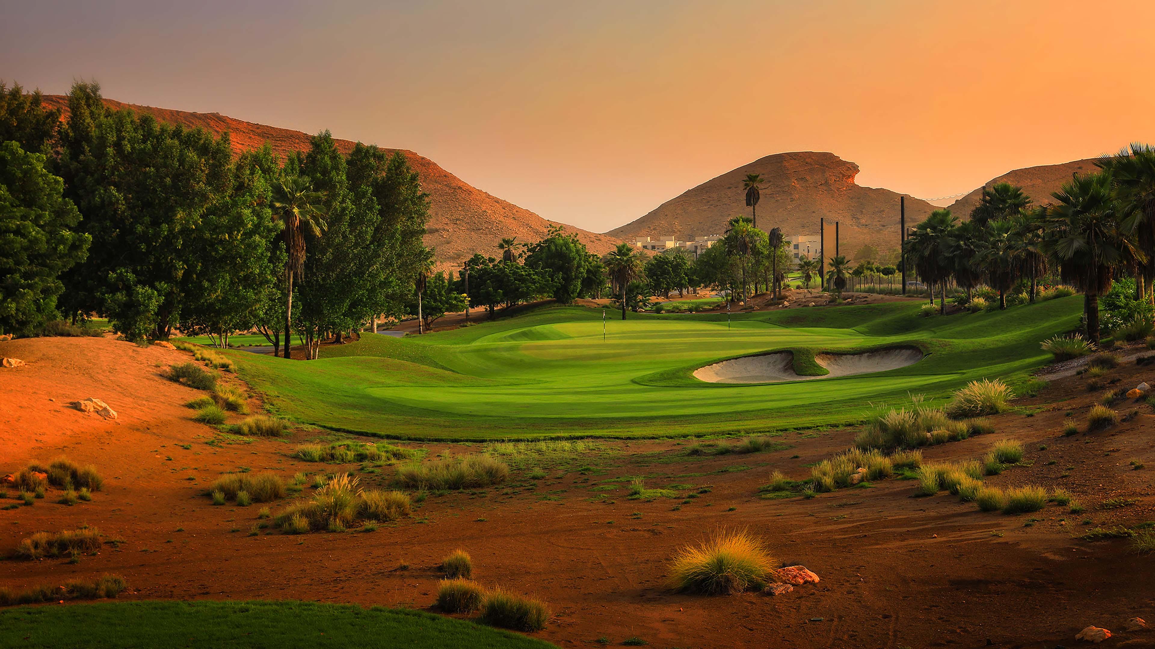 Sun setting over a smooth green surrounded by sand bunkers