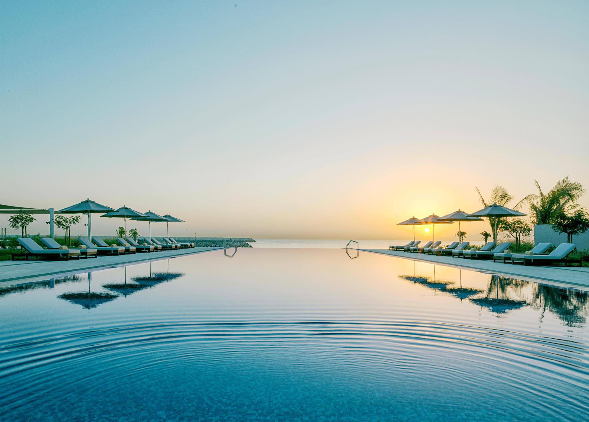 Outdoor swimming pool with the sun setting in the distance