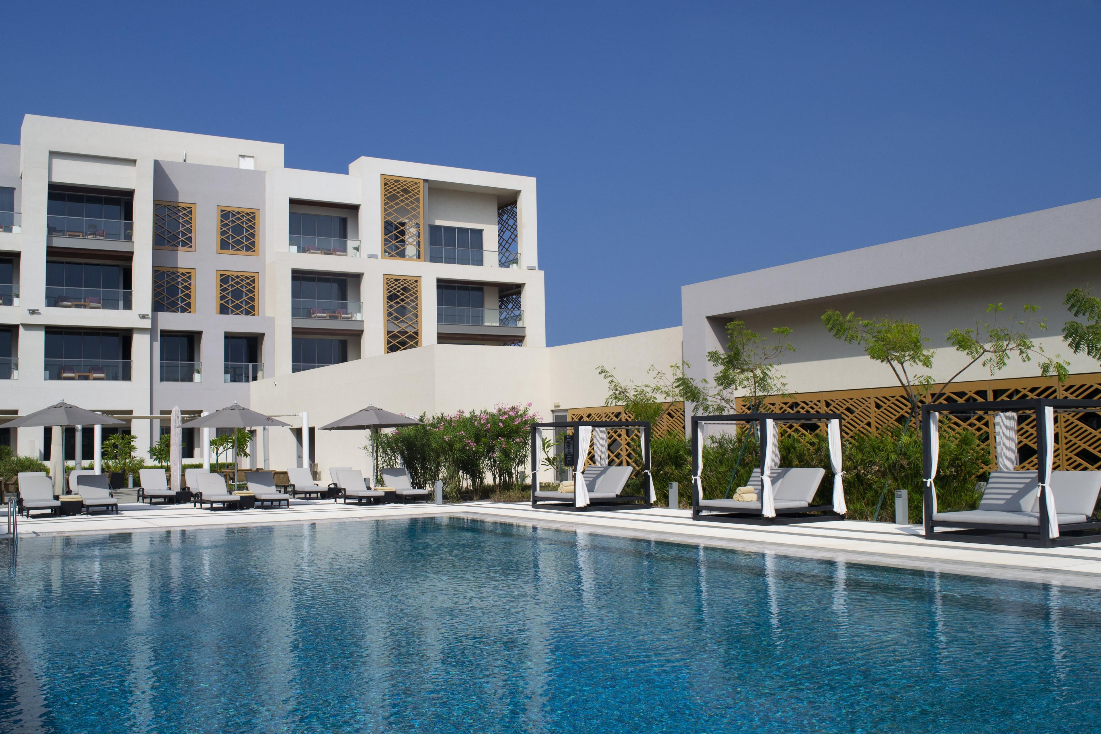 Panoramic view of the Kempinski Hotel Muscat overlooking the outdoor pool surrounded by sunbeds