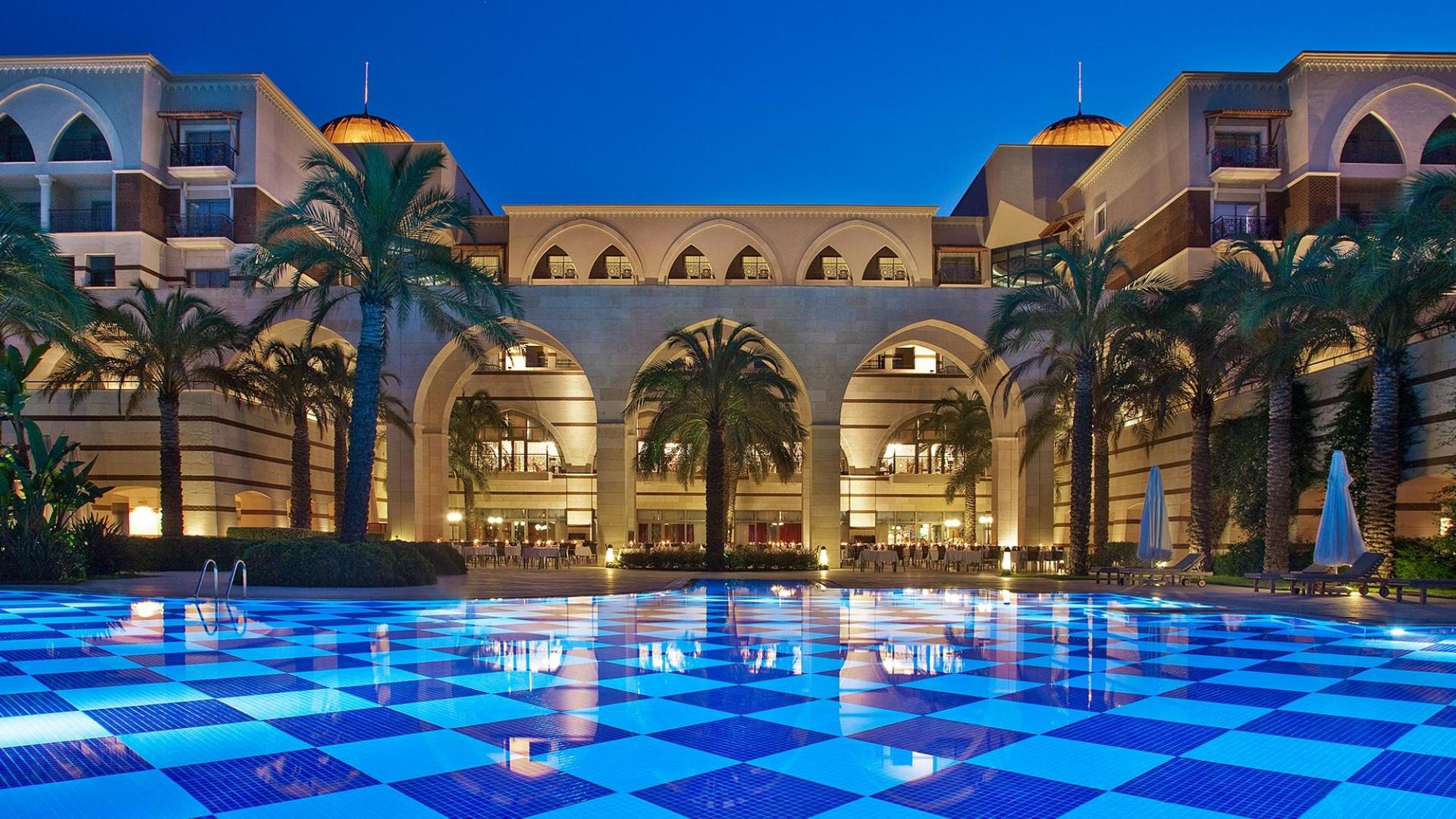 Outdoor pool area with palm trees and showing off the stone archways