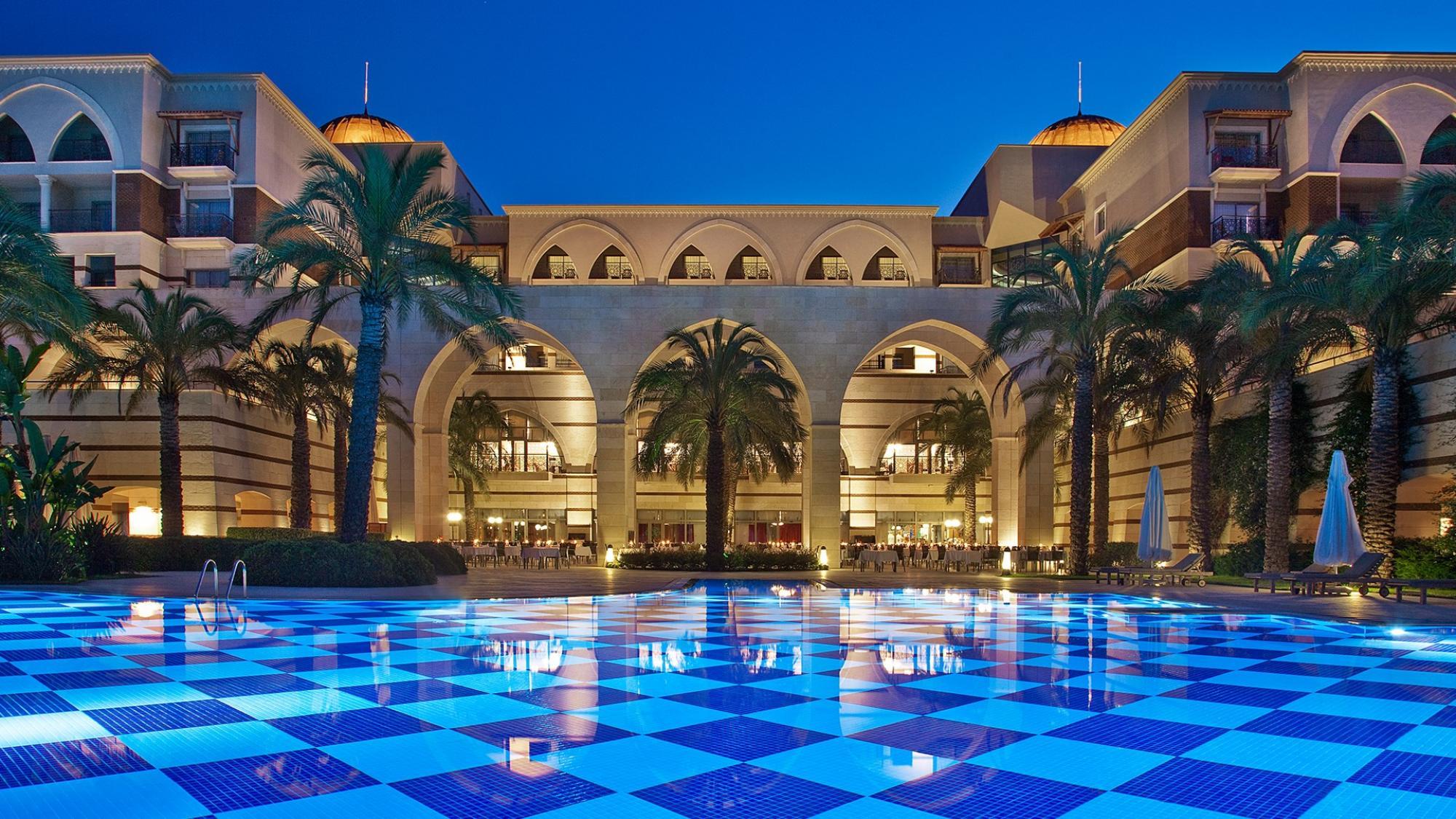 Outdoor pool area with palm trees and showing off the stone archways