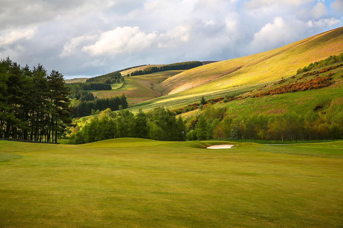 A well maintained fairway nestled with a sand bunker