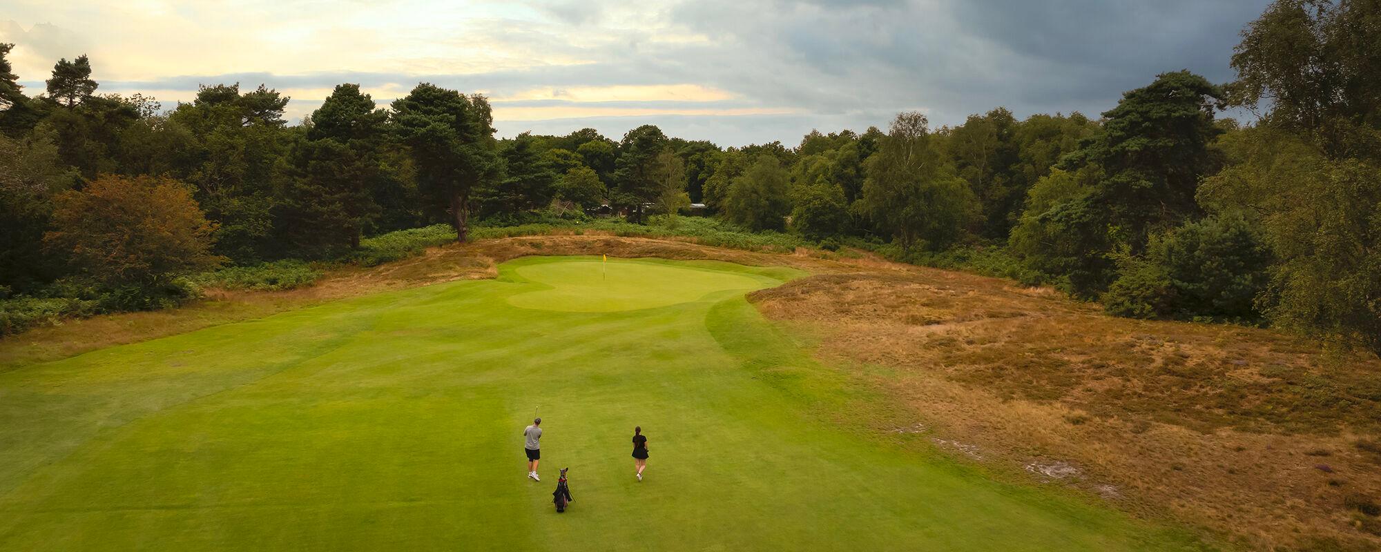 Two players chipping onto a sloping green