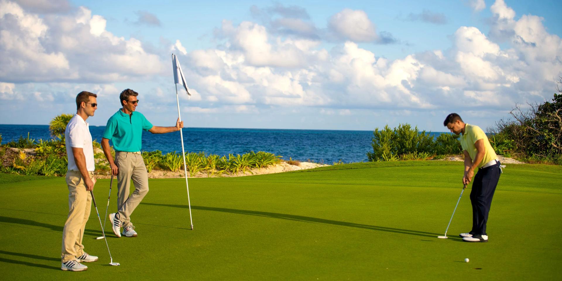 Golfers on a smooth green putting with coastal views