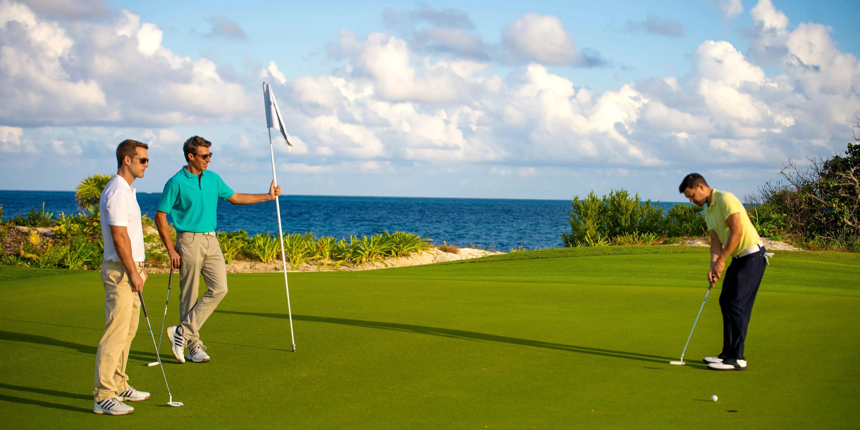 Golfers on a smooth green putting with coastal views