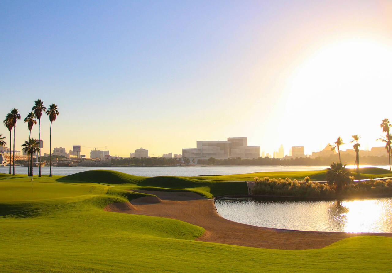 Sun shining onto a well maintained fairway with a sand bunker