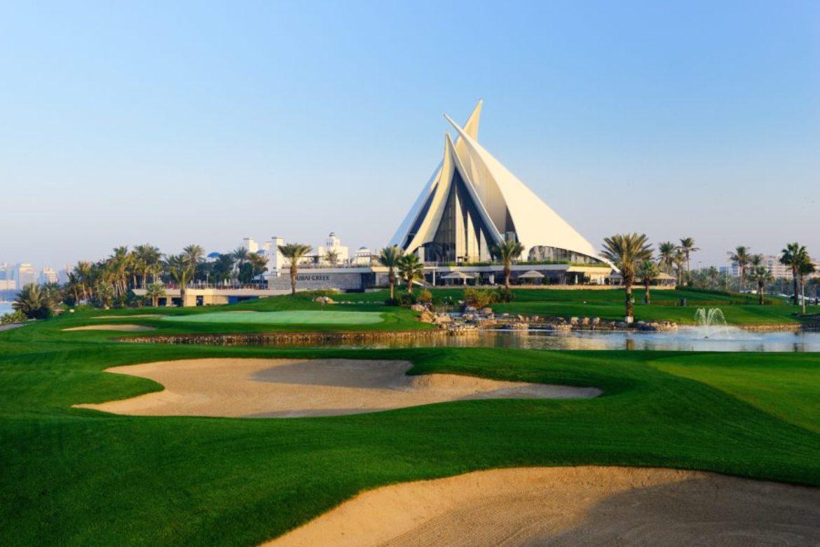 A well maintained fairway nestled with sand bunkers with the clubhouse in the distance