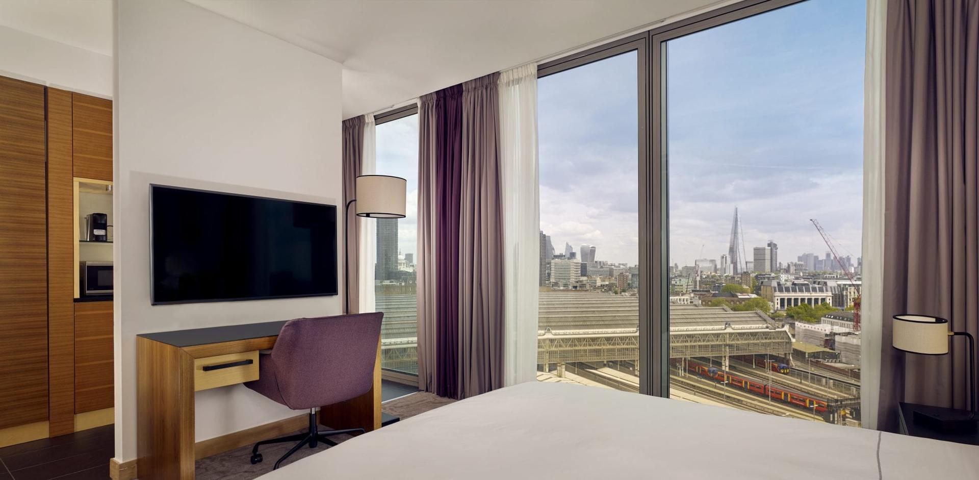 Double bed suite with panoramic window views of the city