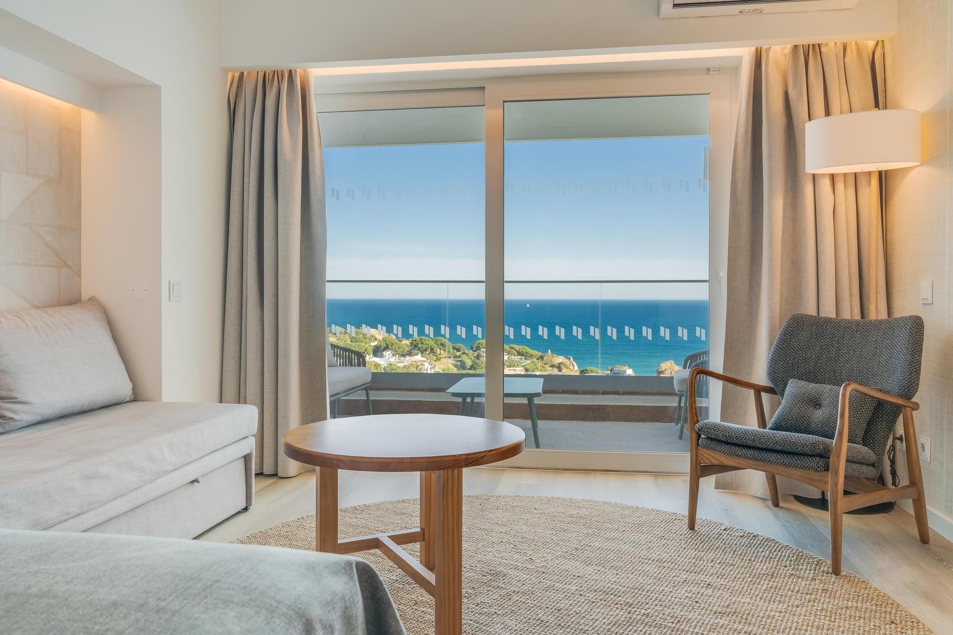 Lounging area as part of a suite leading to a balcony with coastal views