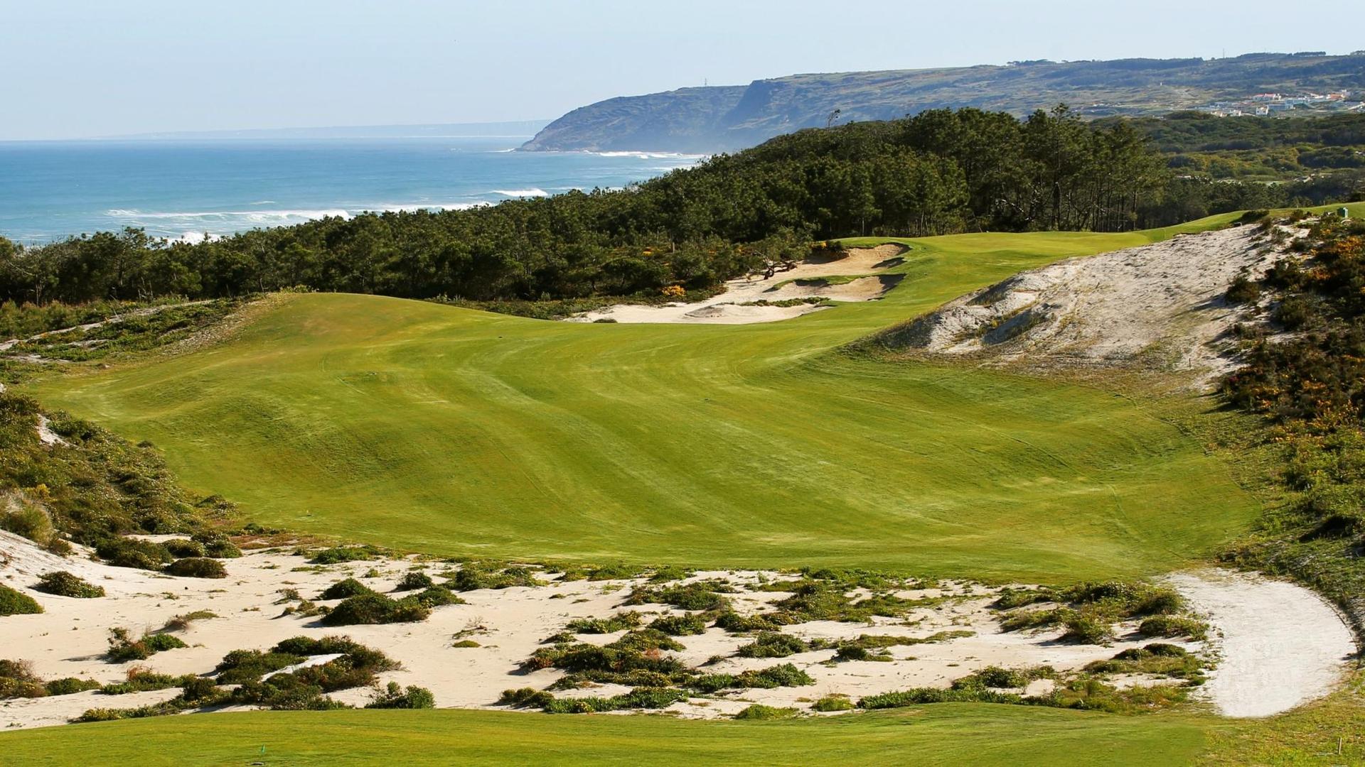 A well maintained fairway surrounded by a sandy rough