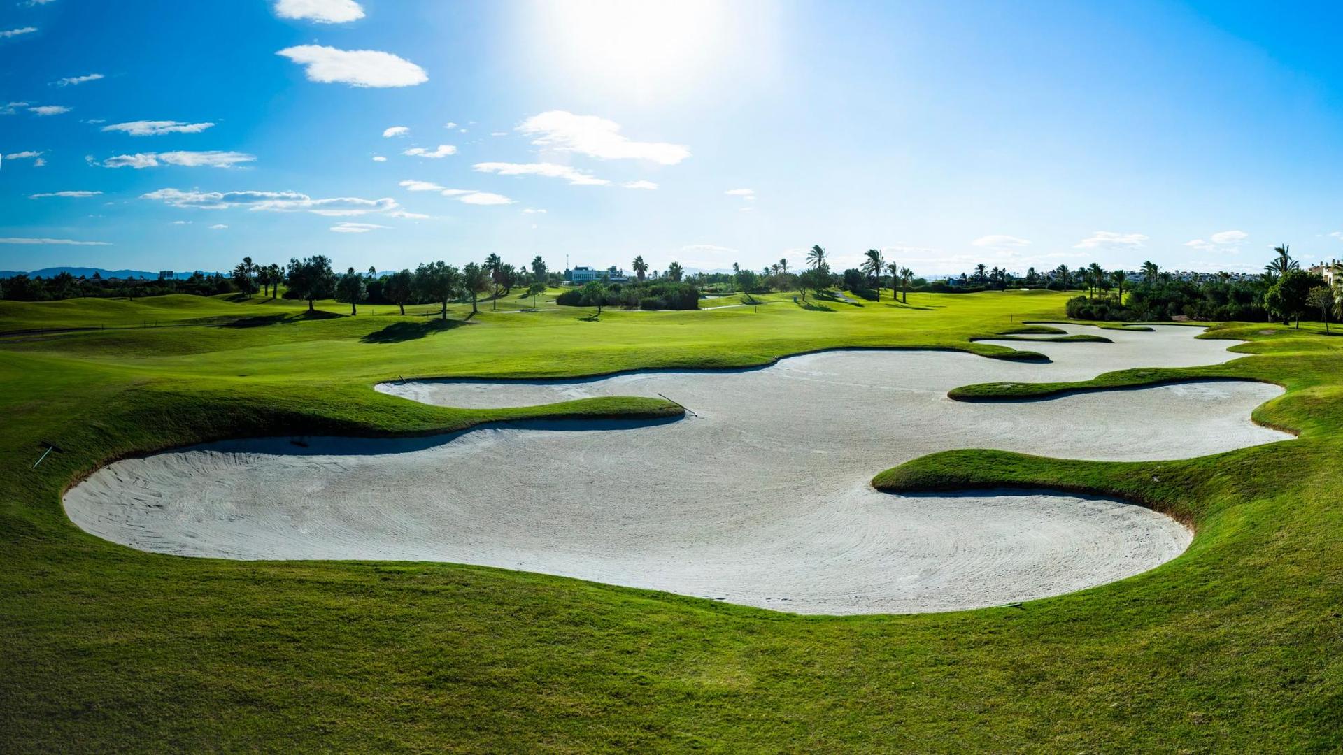 A well maintained fairway nestled with sand bunkers