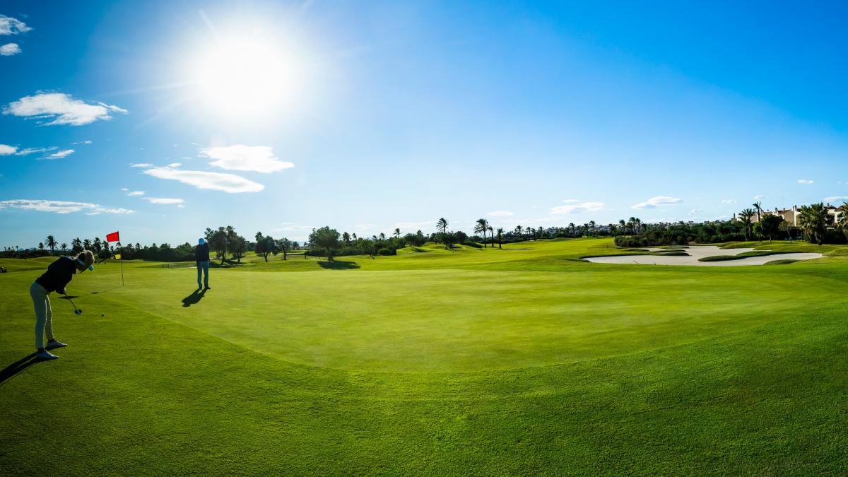 Smooth, manicured green with two players putting