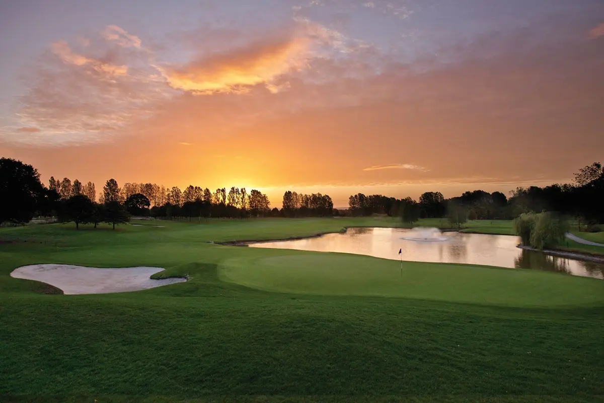 Sun setting over a well maintained fairway next to a water hazard