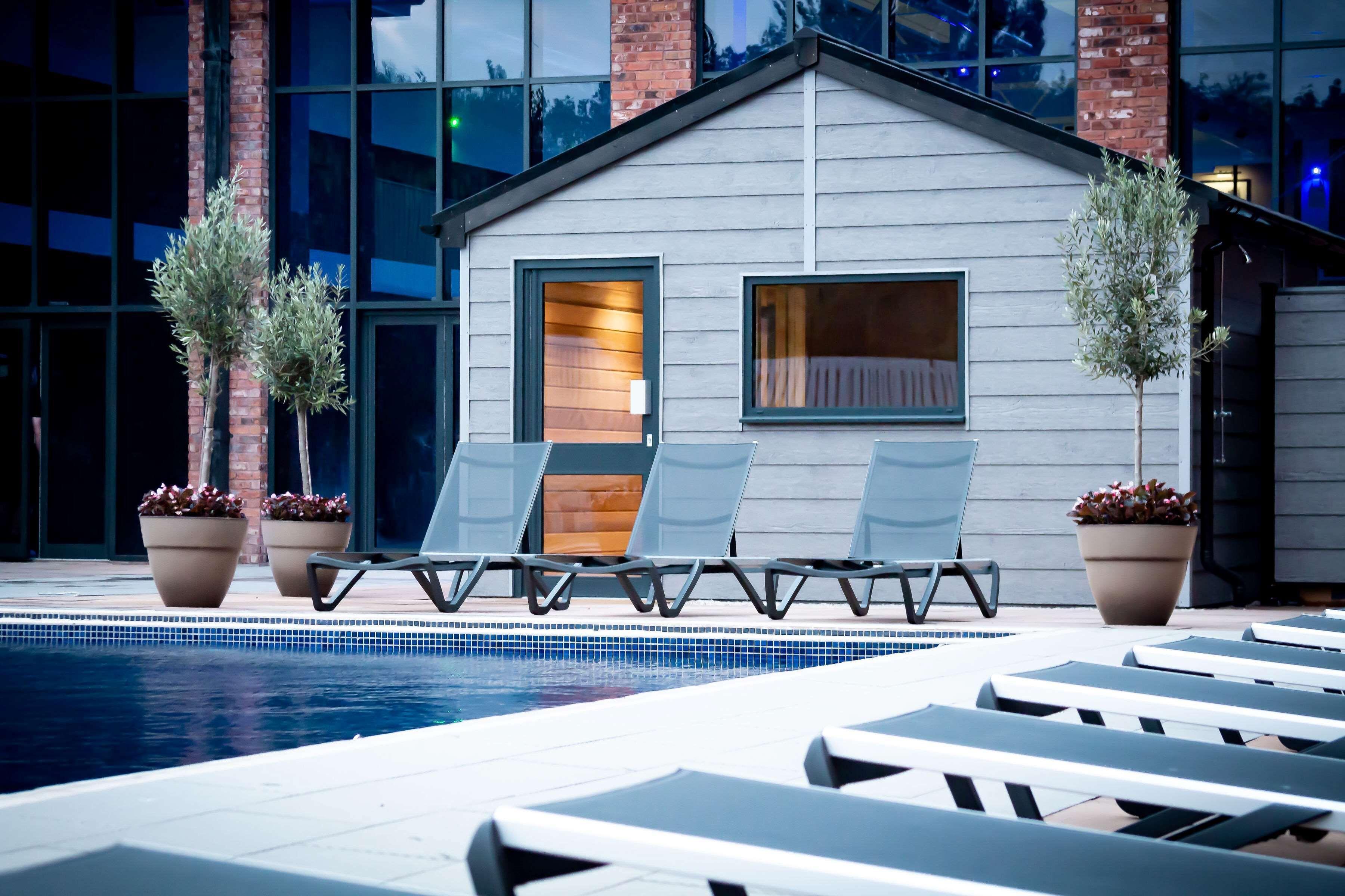 Outdoor swimming pool surrounded by sunbeds at Village Hotel Herons Reach