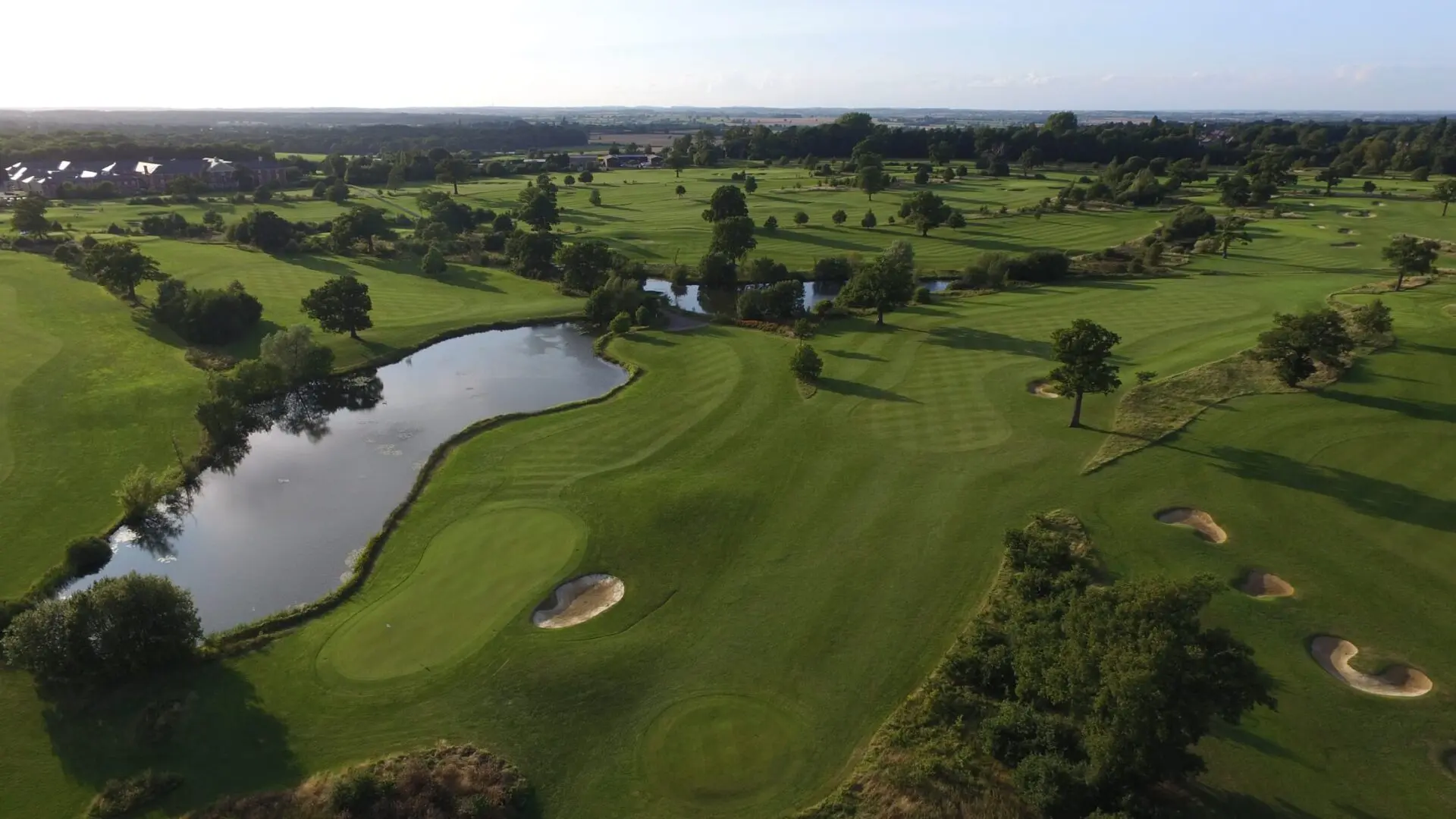 A well maintained fairway nestled with a sand bunker next to a water hazard