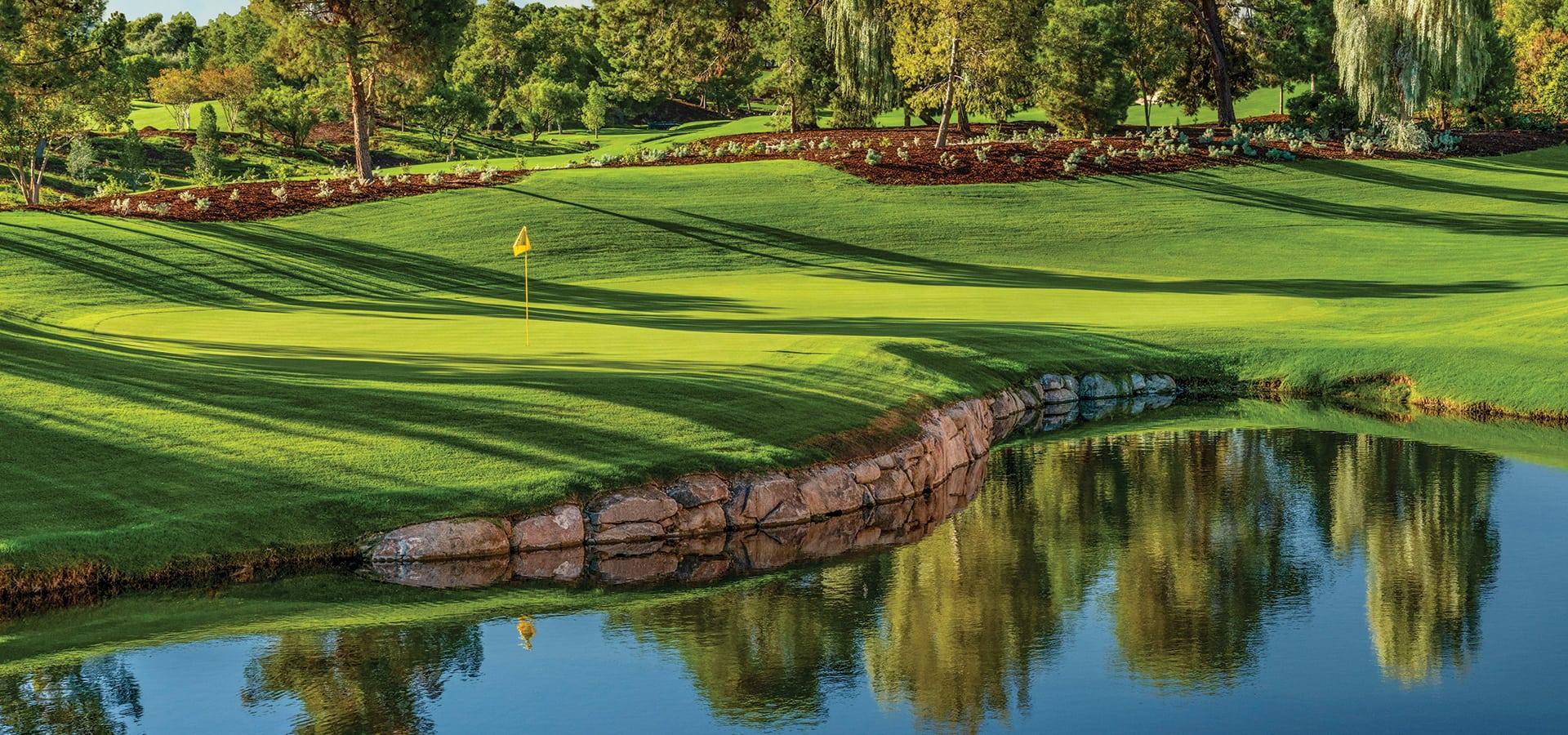 A smooth green next to a water hazard with a yellow flagstick