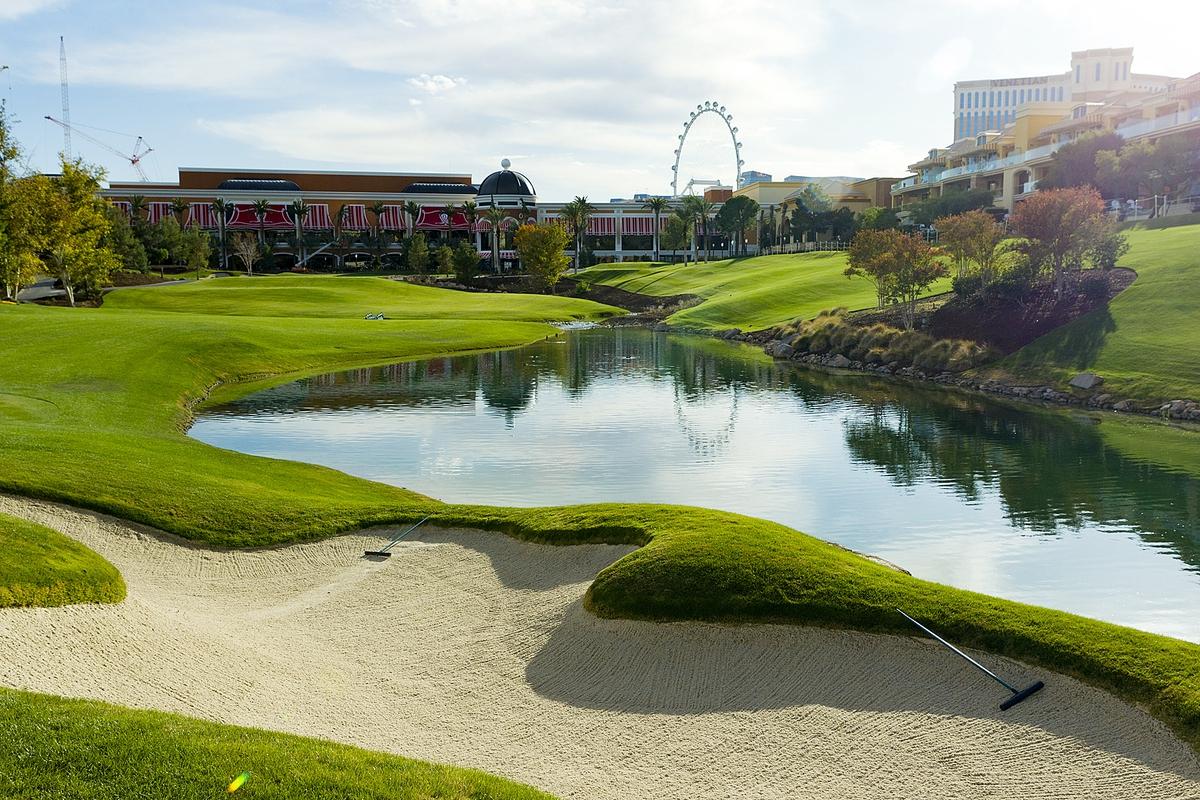 A well maintained fairway nestled with a sand bunker next to a water hazard