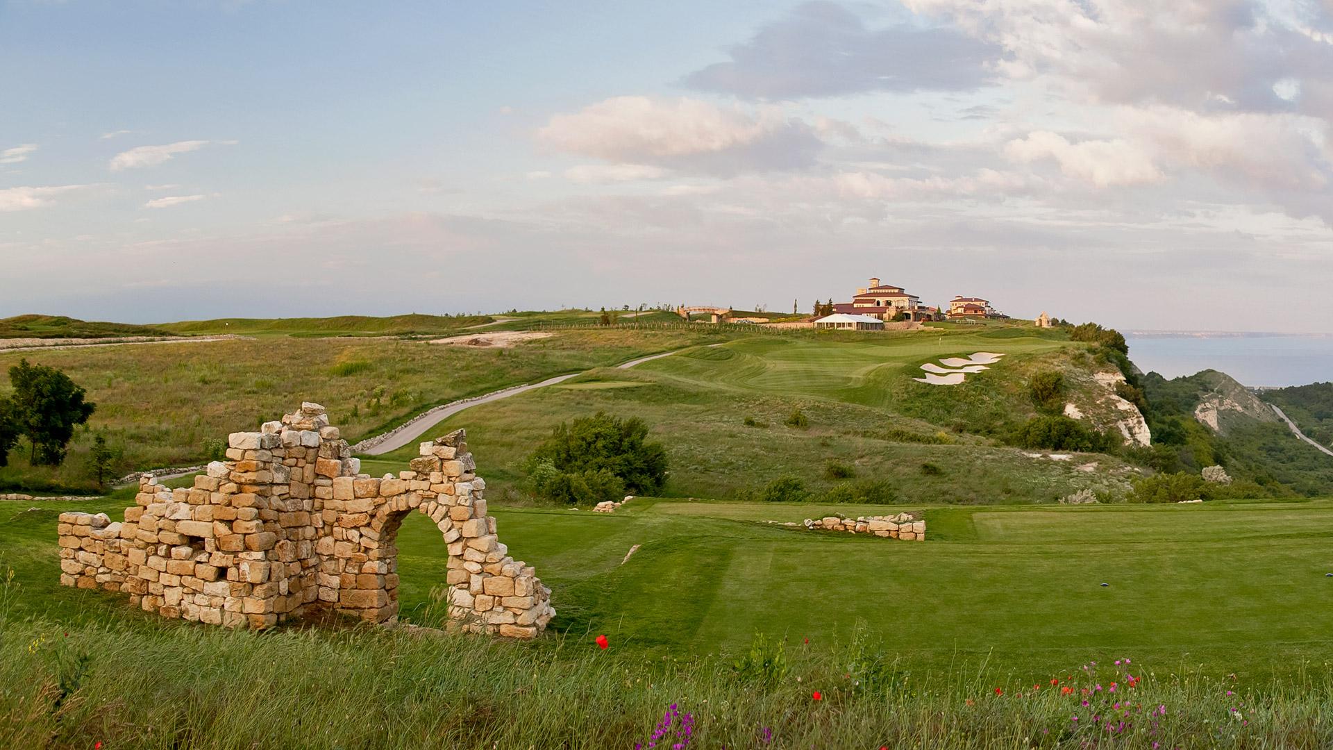 A well maintained fairway with a historic stone piece on the course
