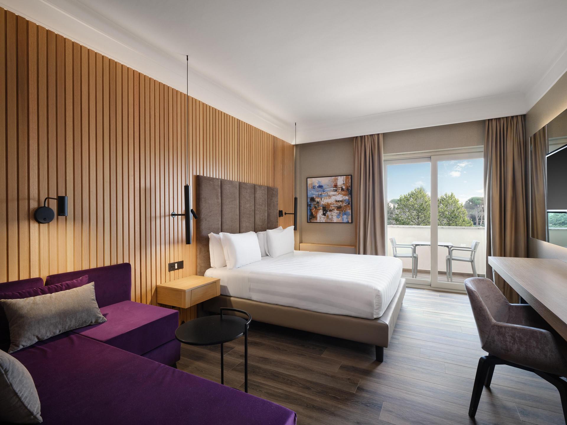 Double bed suite with a purple sofa and balcony views at Crowne Plaza Rome