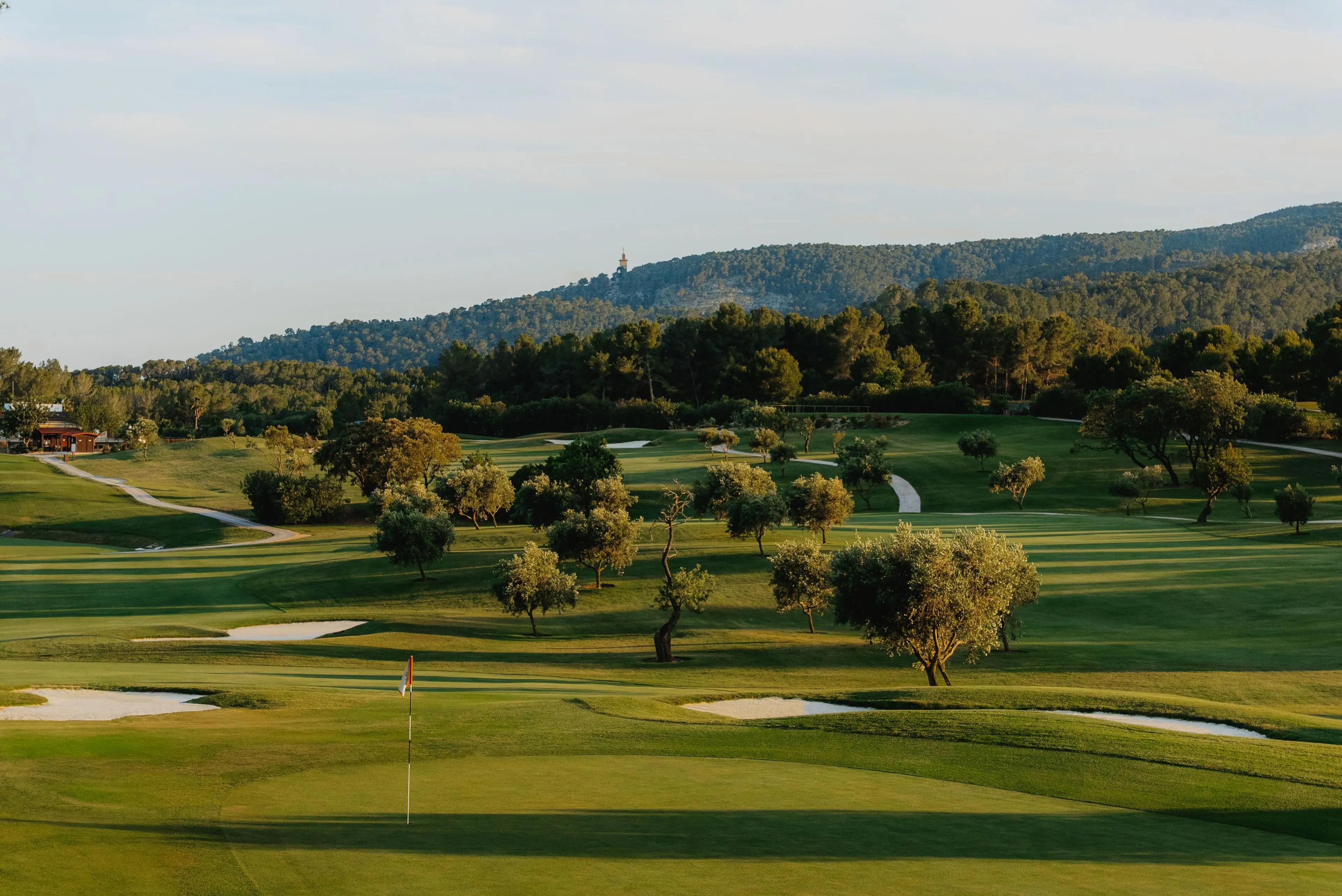A well maintained fairway nestled with sand bunkers leading to a smooth green