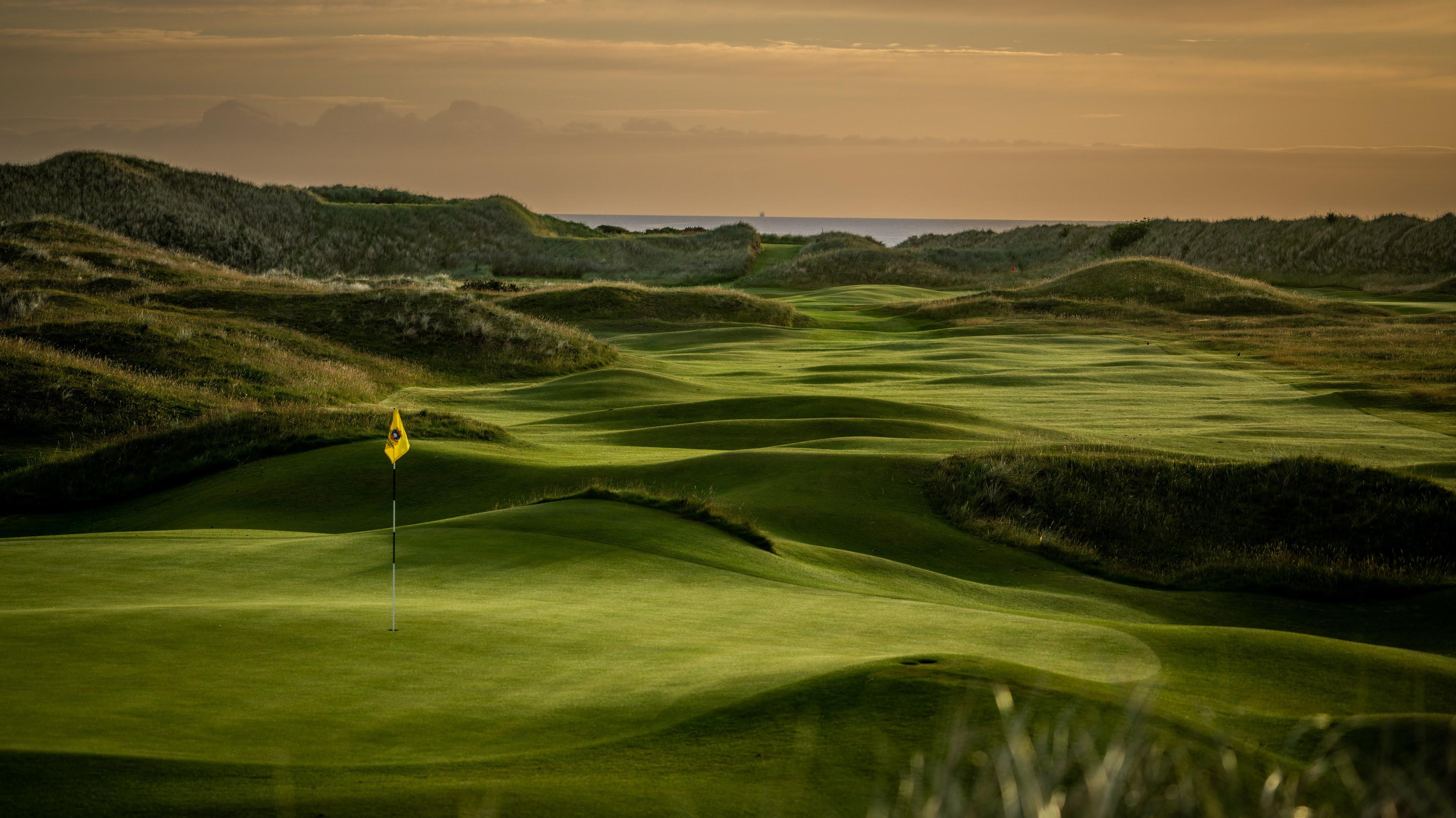 Rolling dunes leading towards a smooth green
