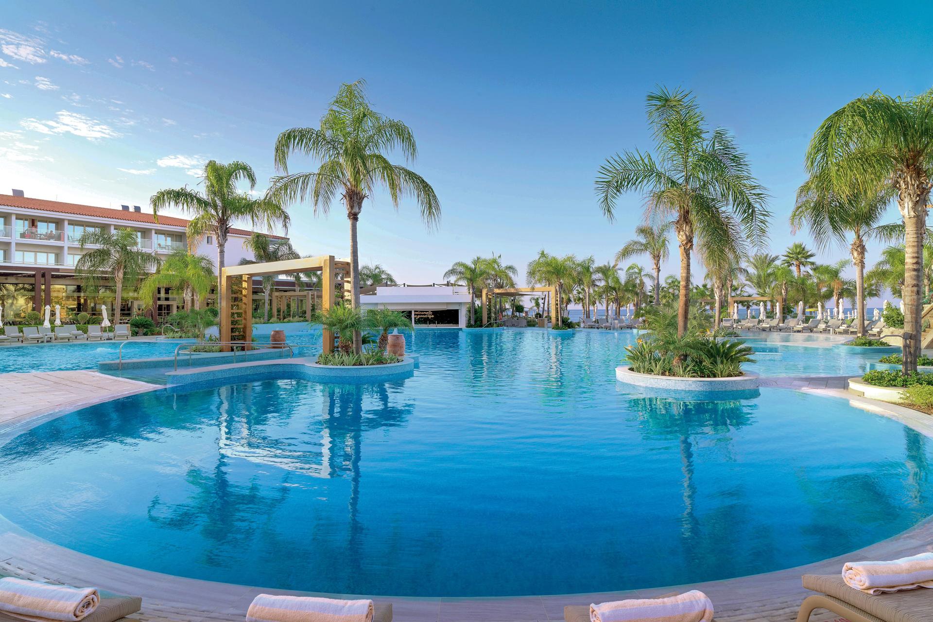 Outdoor swimming pool surrounded by palm trees at Olympic Lagoon Resort