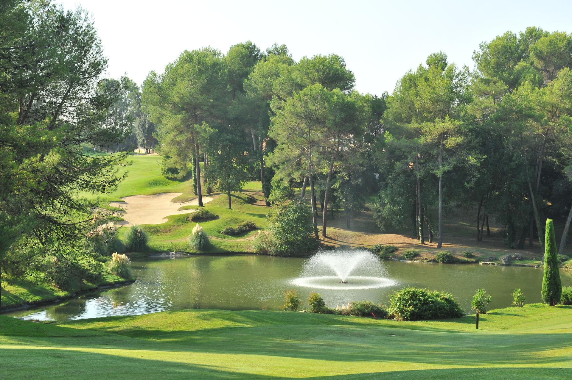 A well maintained fairway with a water hazard designed with a water fountain