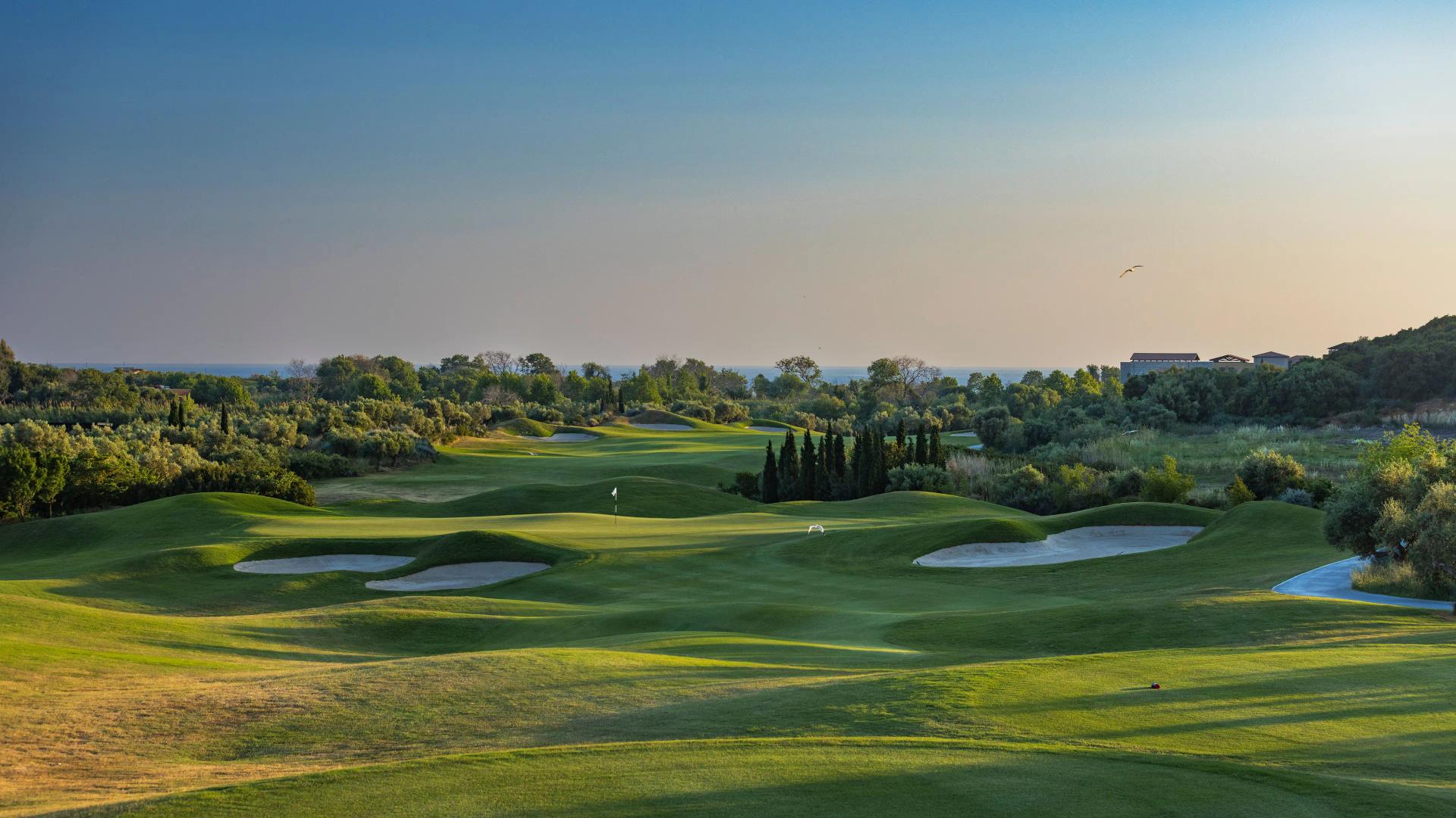 A well maintained fairway nestled with sand bunkers leading to a smooth green